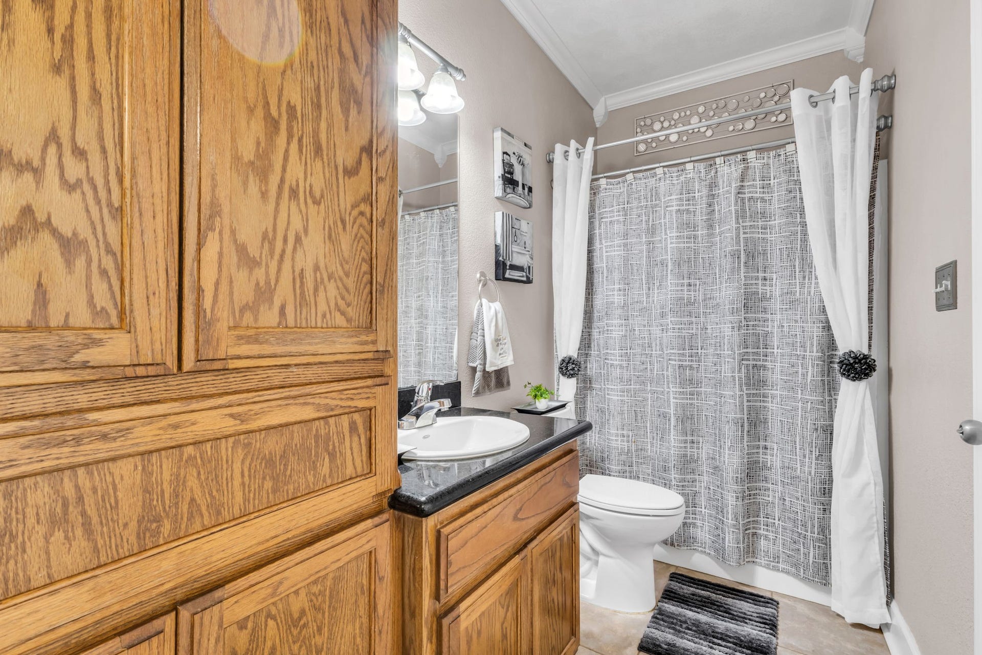 11010 Madison Court, Beaumont, TX 77705 Adjoining guest bathroom features a tub and shower combination, wood cabinetry, dark countertop, and additional built-in storage for everyday convenience.