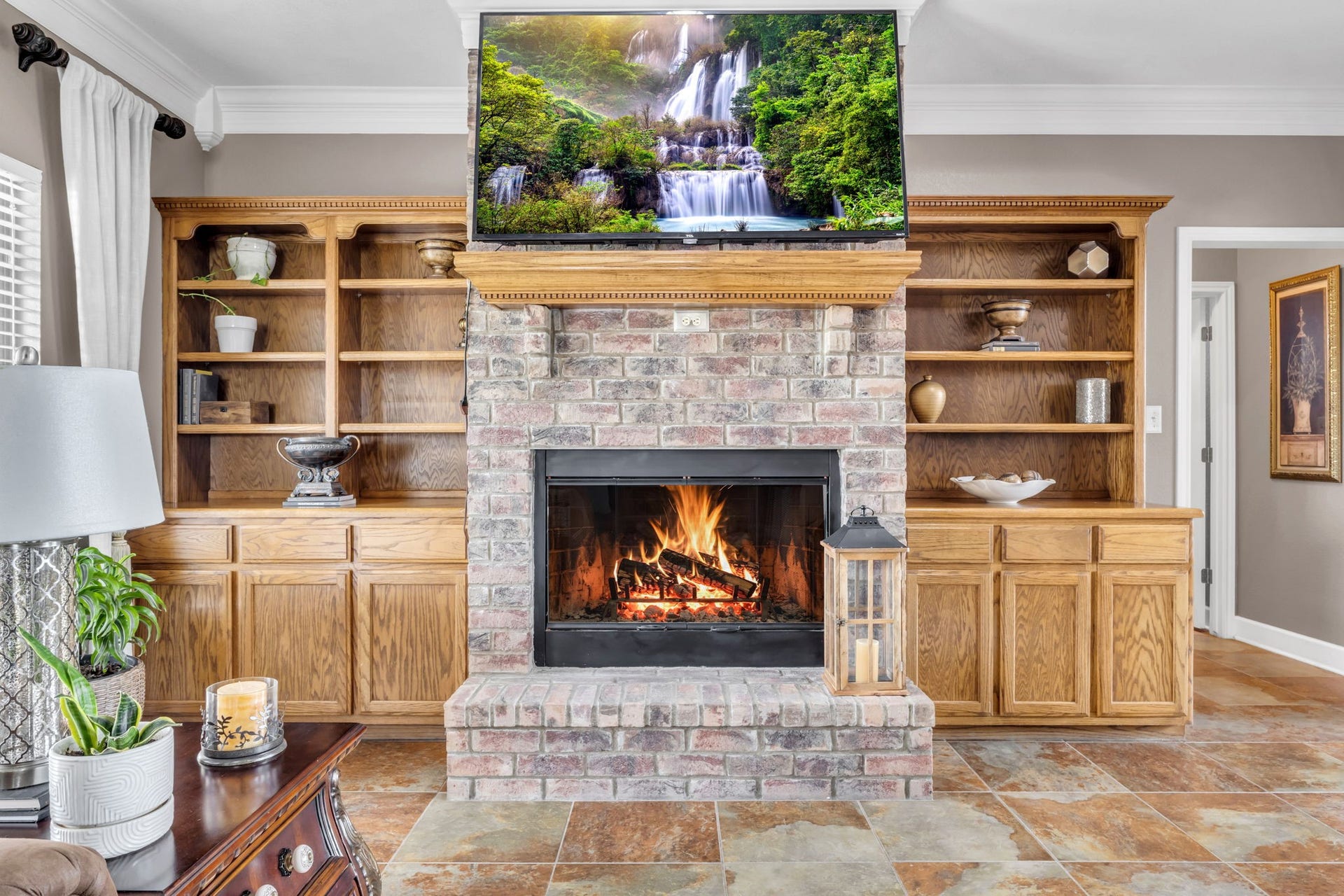 11010 Madison Court, Beaumont, TX 77705 Beautiful brick fireplace serves as the focal point of the living room, complemented by wood built-ins with open shelving and lower cabinets for additional storage.
