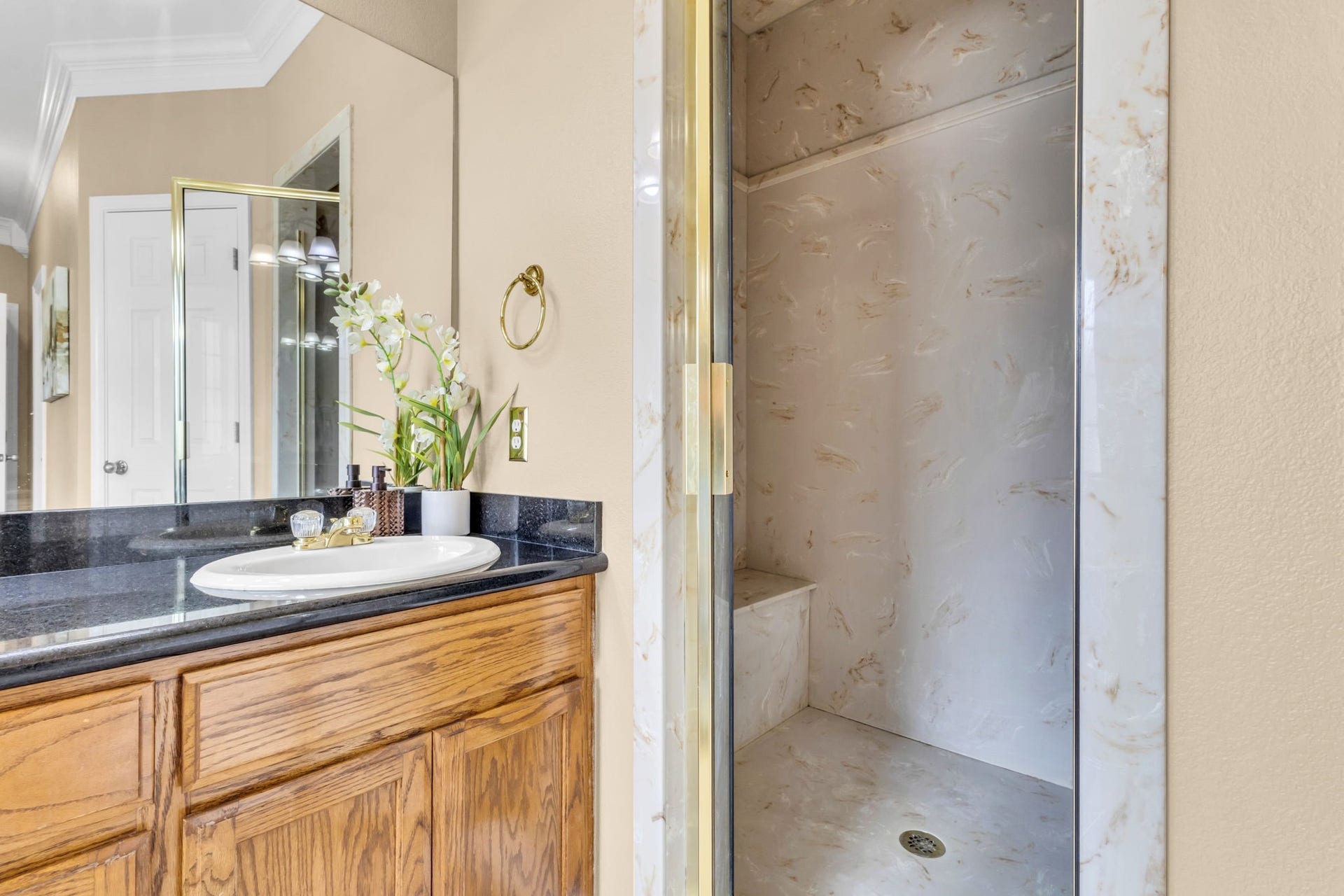 11010 Madison Court, Beaumont, TX 77705 Primary bathroom features a separate glass-enclosed shower with built-in bench, decorative surround, and spacious vanity with dark countertops and ample cabinet storage.
