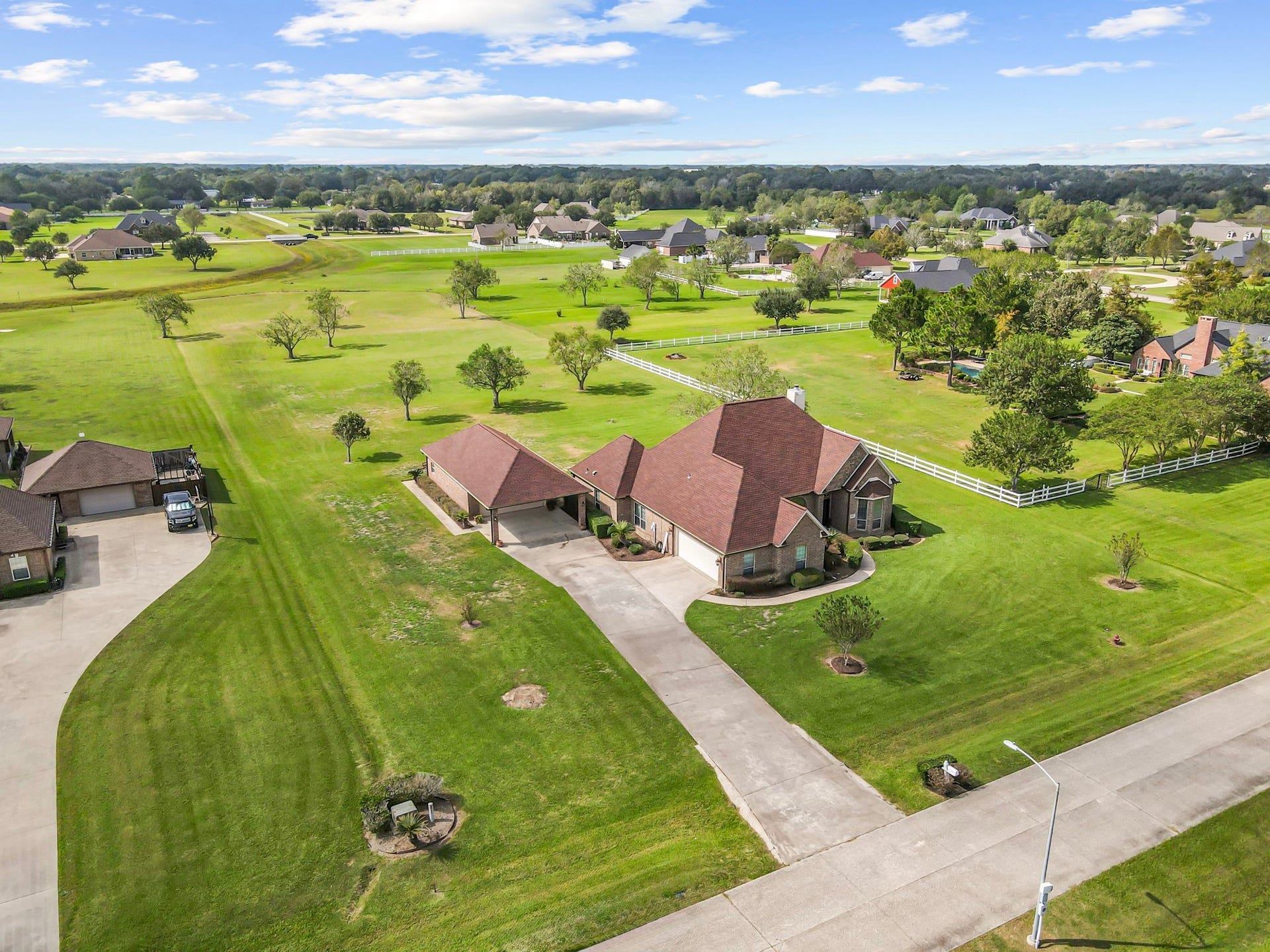 11010 Madison Court, Beaumont, TX 77705 Another stunning aerial view highlighting the property's expansive 2+ acres, attractive brick exterior, and detached garage with covered parking. Surrounded by open green space and mature trees, this property offers room to spread out while enjoying the beauty of its spacious surroundings.