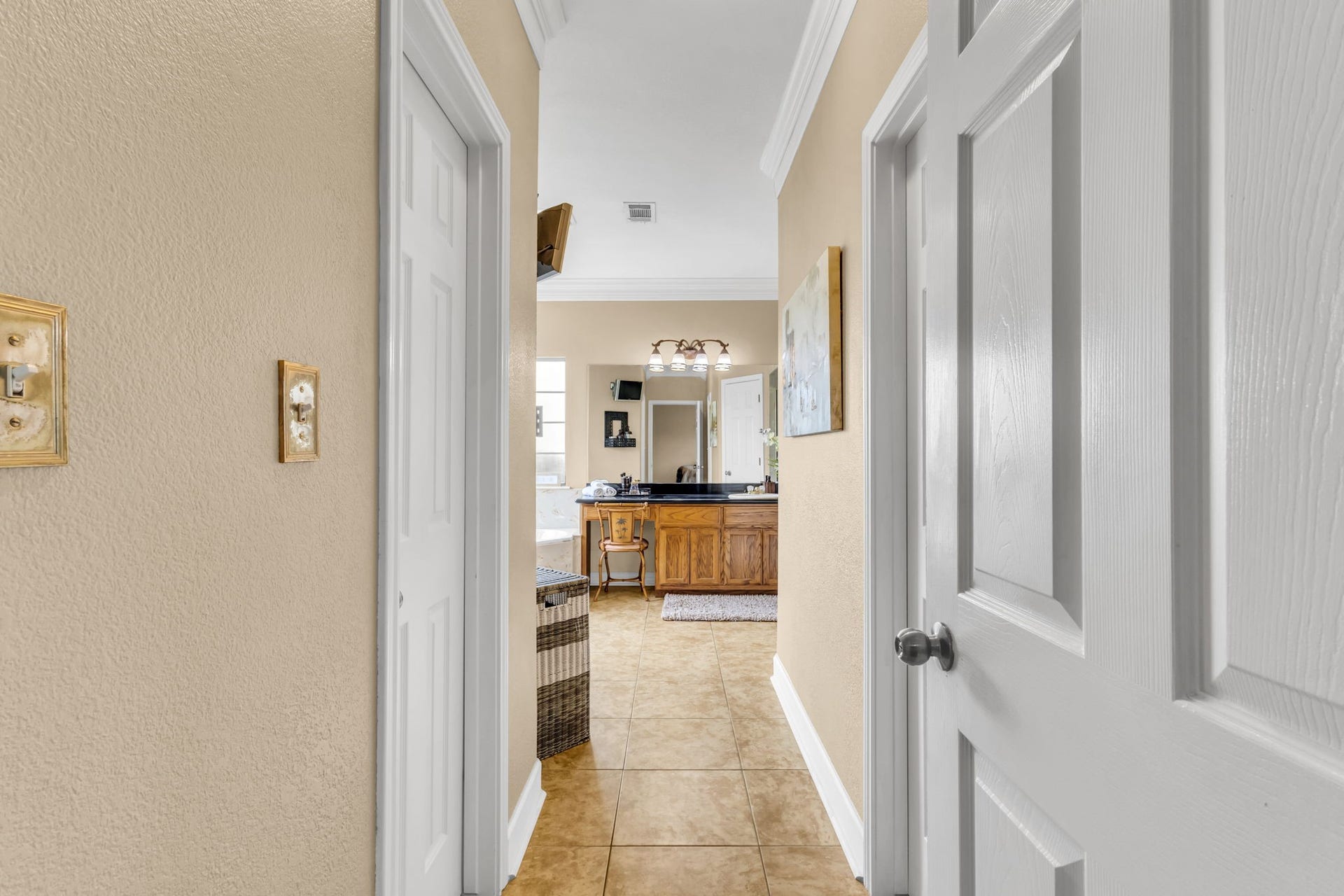 11010 Madison Court, Beaumont, TX 77705 Private entry to the primary bathroom featuring tile flooring, crown molding, and convenient access to the vanity and adjoining his/her walk in closets.