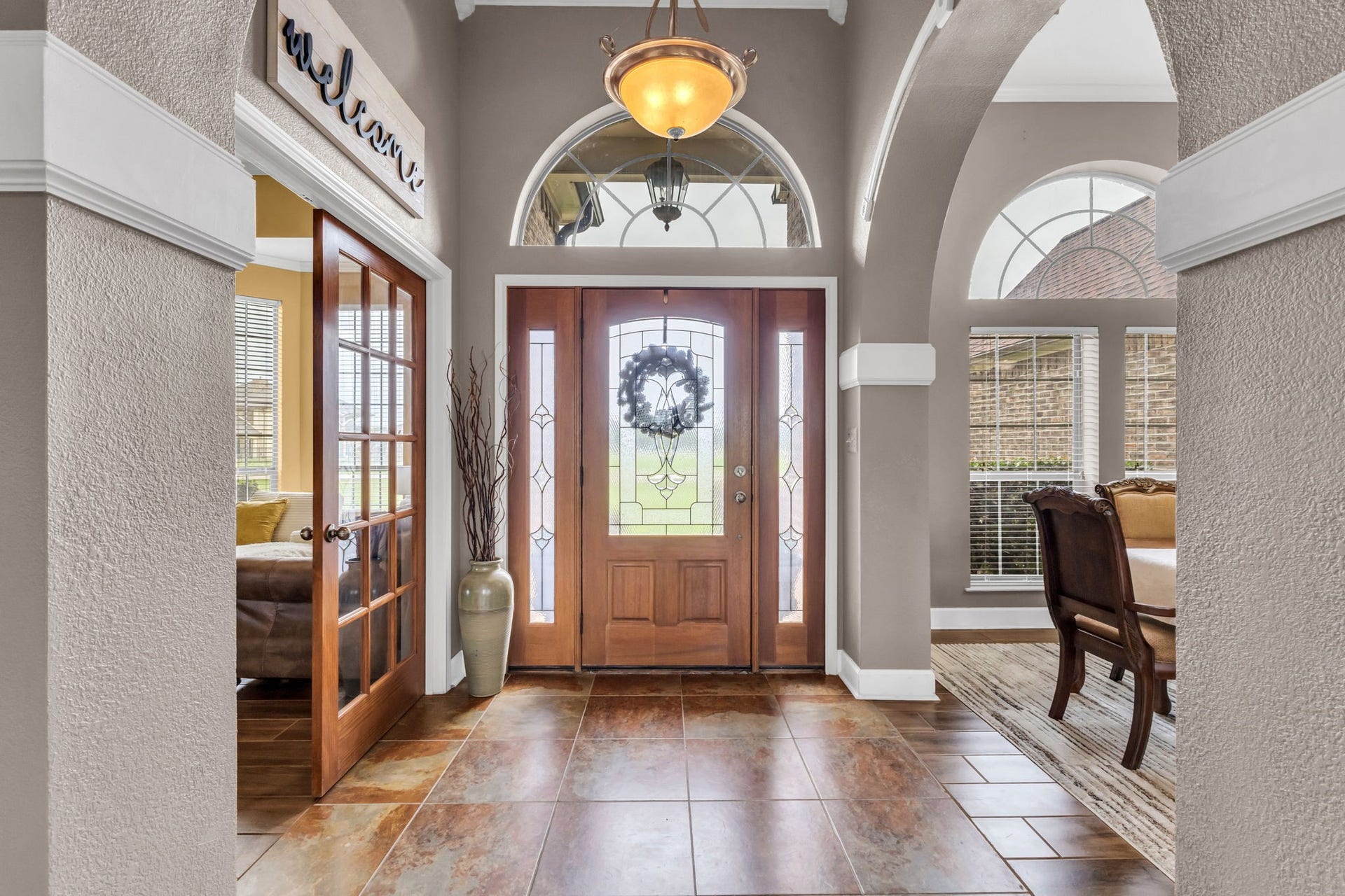 11010 Madison Court, Beaumont, TX 77705 Inviting entryway featuring decorative tile flooring, high ceilings, arched windows, and elegant architectural details. French doors lead to a separate room, while an open archway provides access to the formal dining area.