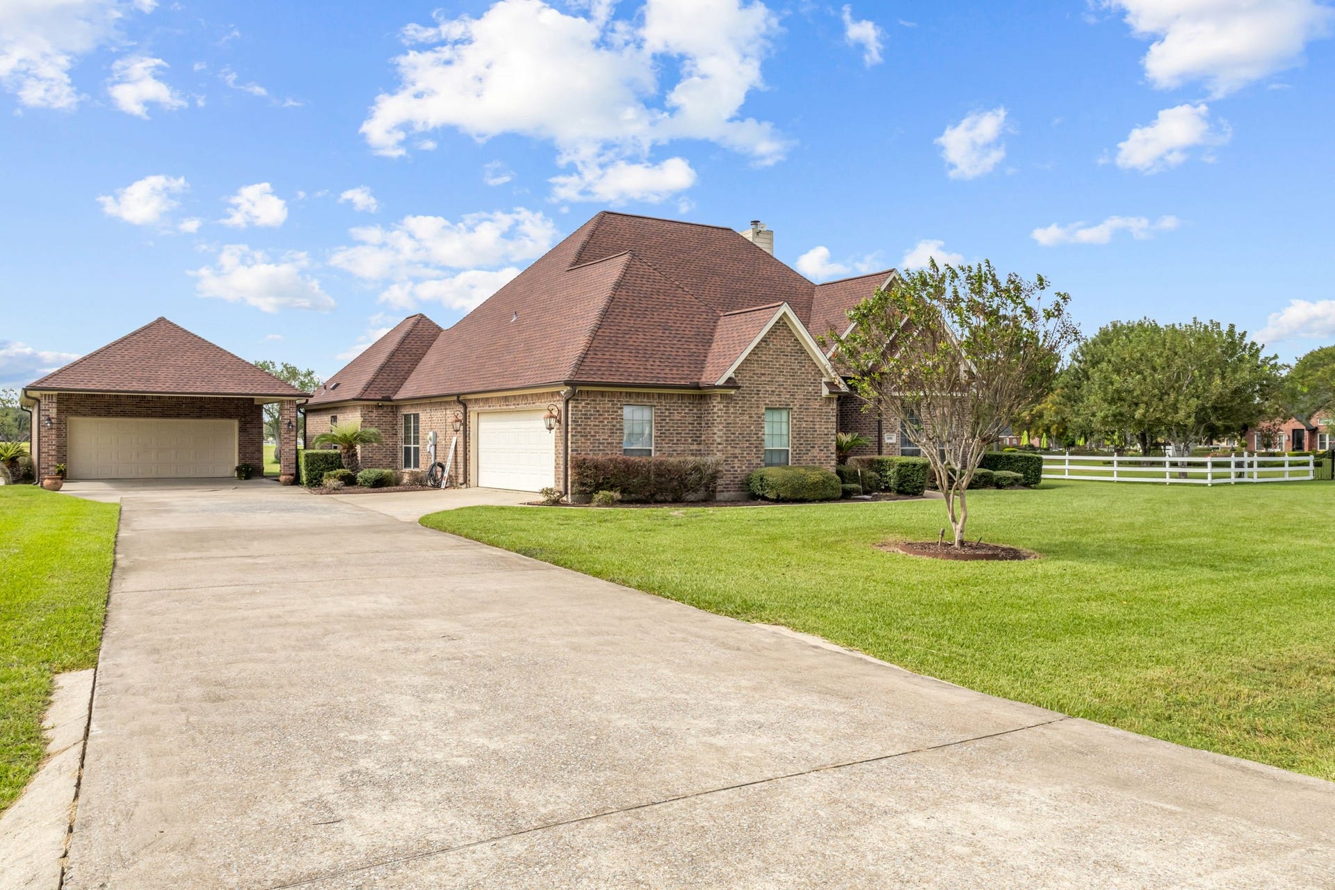 11010 Madison Court, Beaumont, TX 77705 Side view highlighting the extended concrete driveway, attached garage, and additional detached two-car garage, providing ample parking space and convenient access.