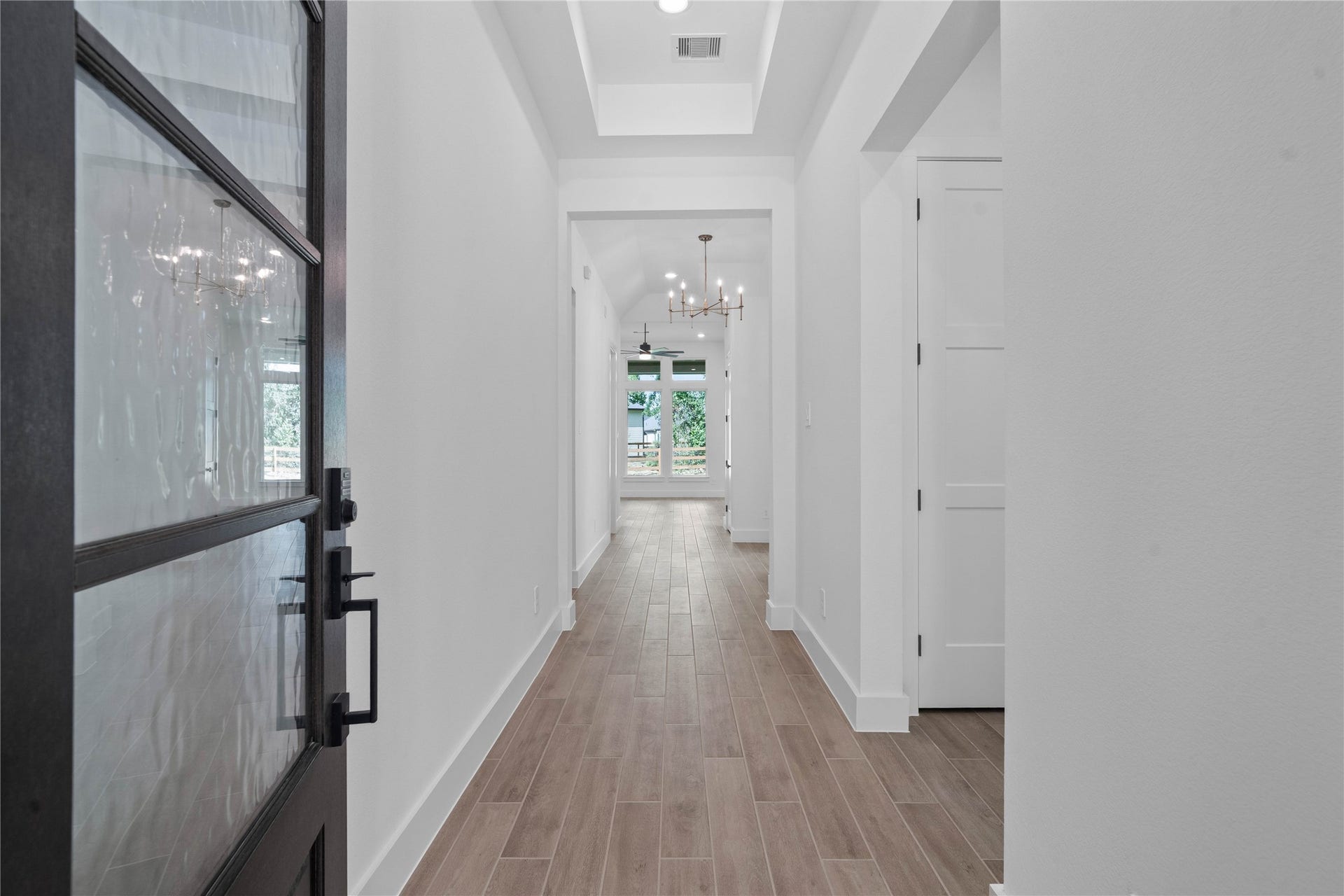 17728 Gold Saddle Lane, Magnolia, TX 77354 A bright, elongated foyer features a grand recessed tray ceiling and warm wood tile flooring that instantly establishes a welcoming, inviting atmosphere upon entry.
