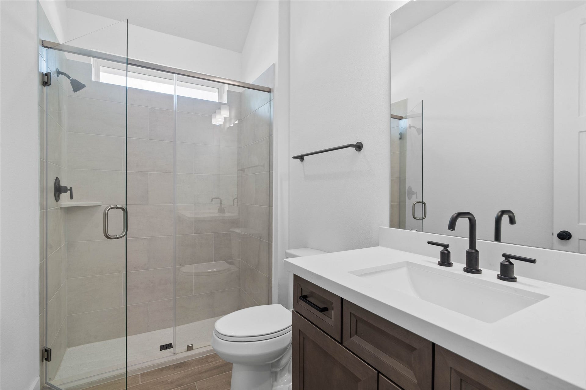 17728 Gold Saddle Lane, Magnolia, TX 77354 This well-appointed secondary bathroom features a sleek single vanity with a crisp white countertop and modern fixtures, set against the stunning tile in the large walk-in shower.