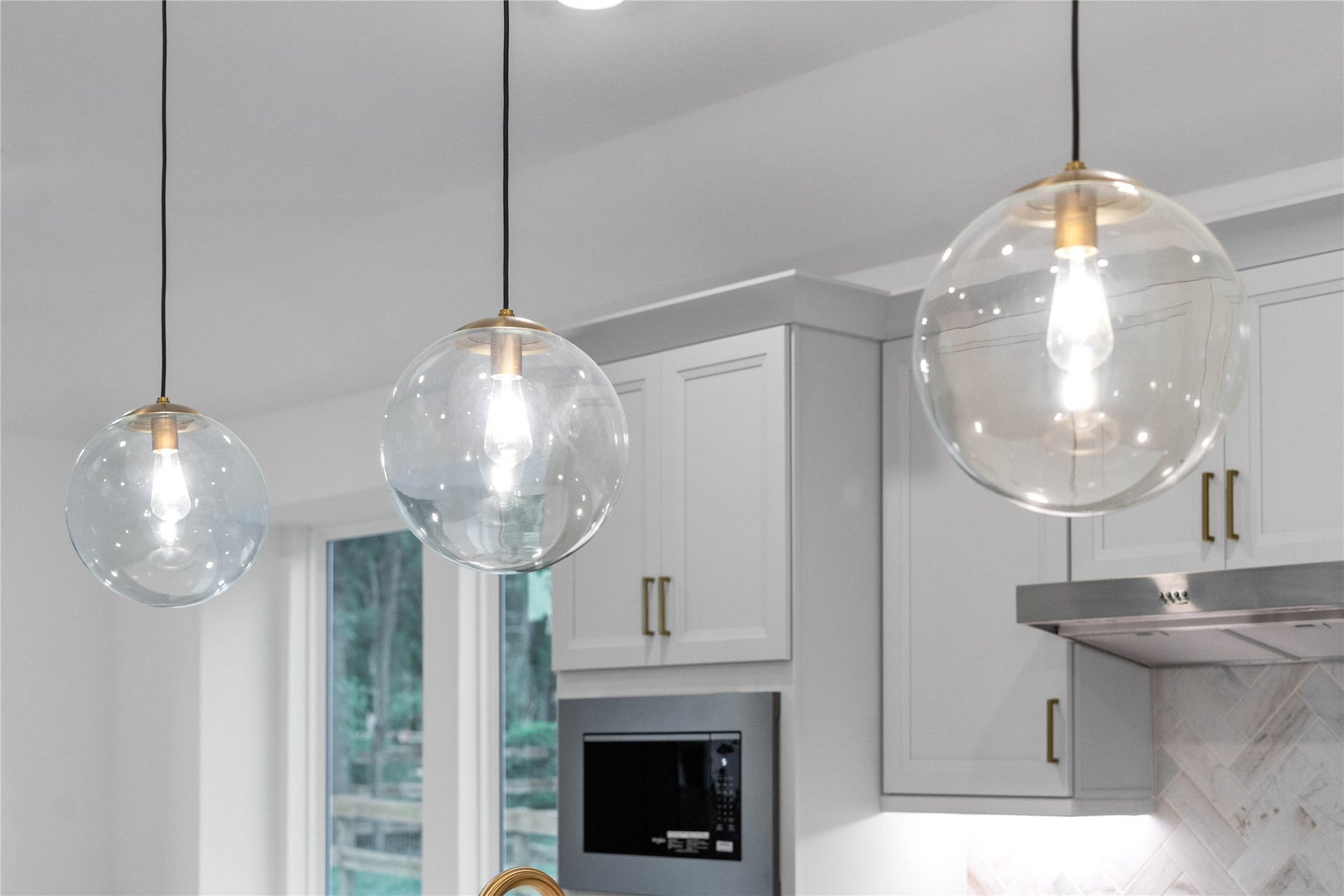 17728 Gold Saddle Lane, Magnolia, TX 77354 A trio of chic, clear glass globe pendant lights hangs elegantly over the kitchen island, perfectly combining modern style with bright illumination.