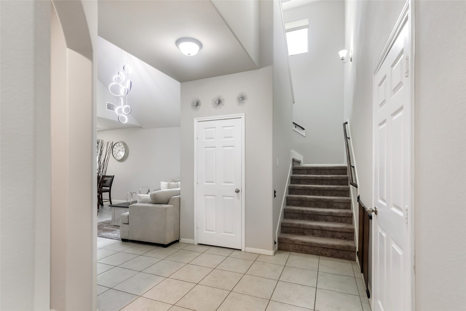 Bright two-story foyer welcomes guests with high ceilings, tile flooring and a view toward the open living spaces.