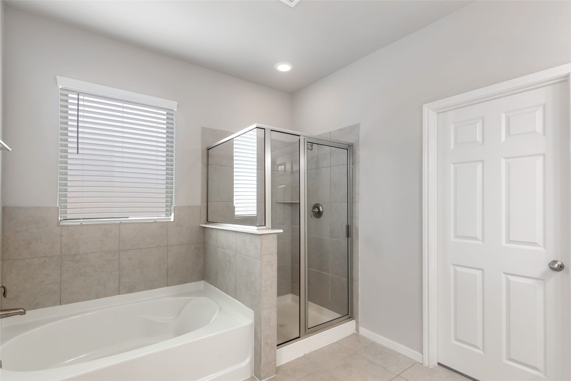 Bright primary bathroom offers a relaxing soaking tub, separate glass-enclosed shower and dual-sink vanity.