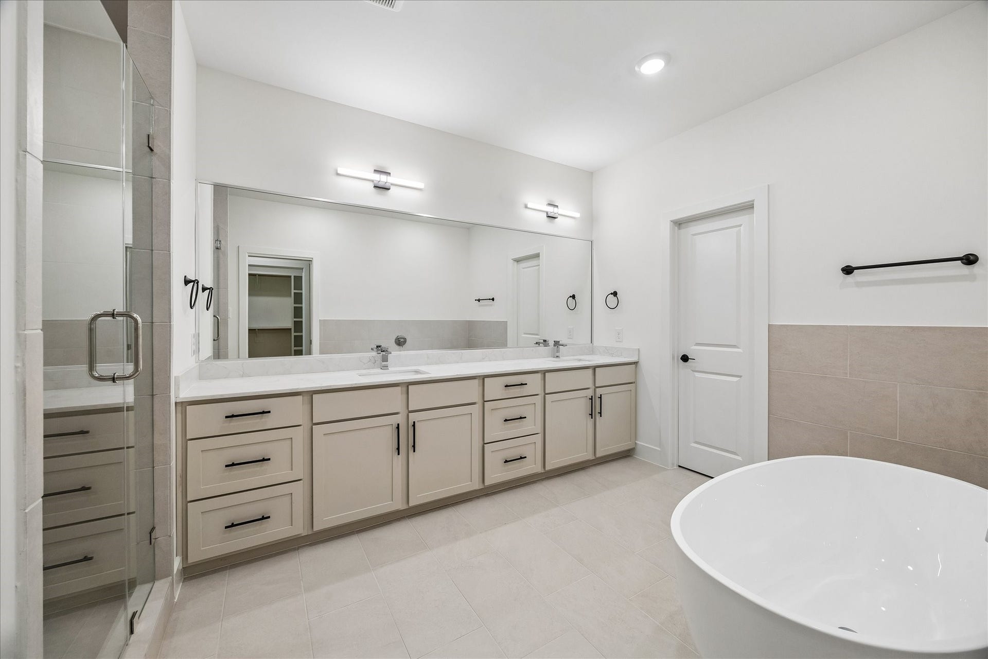 Spacious primary bathroom featuring dual vanities, a freestanding soaking tub, glass-enclosed shower, and modern finishes throughout.