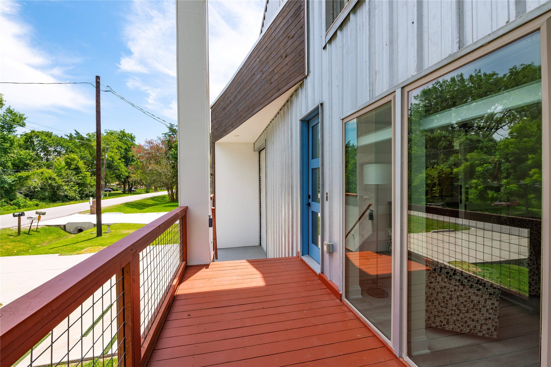 13149 W 6th Street, Santa Fe, TX 77510 Oversized covered front porch decking features 3/4" conduit horizontal railing and dusk to dawn step accent lights. 8'x20' stained wood accent wall framing the garage.