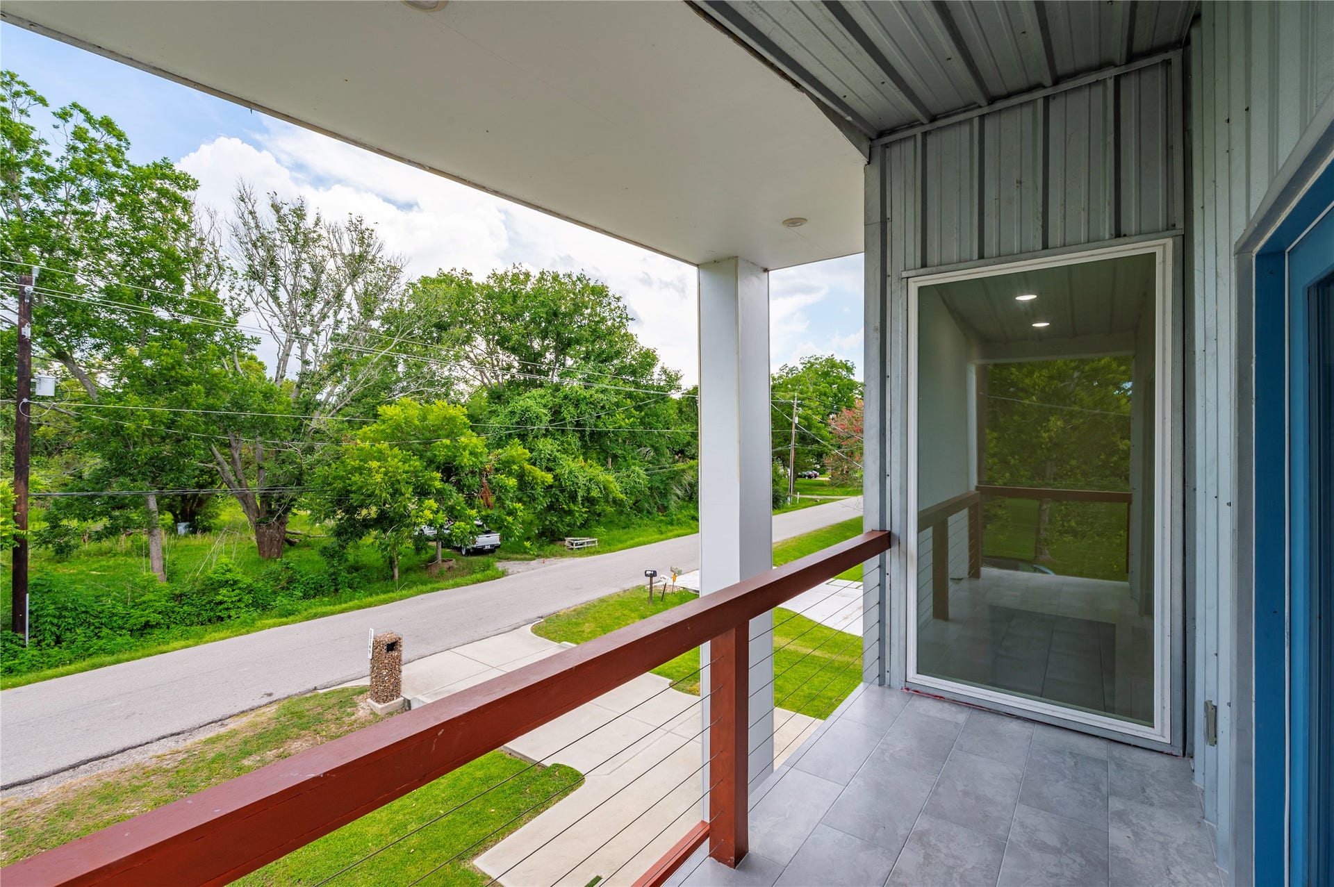13149 W 6th Street, Santa Fe, TX 77510 Private 2nd story covered patio features 3/4" conduit horizontal railing on balcony overlooking the front of the property with tile flooring.