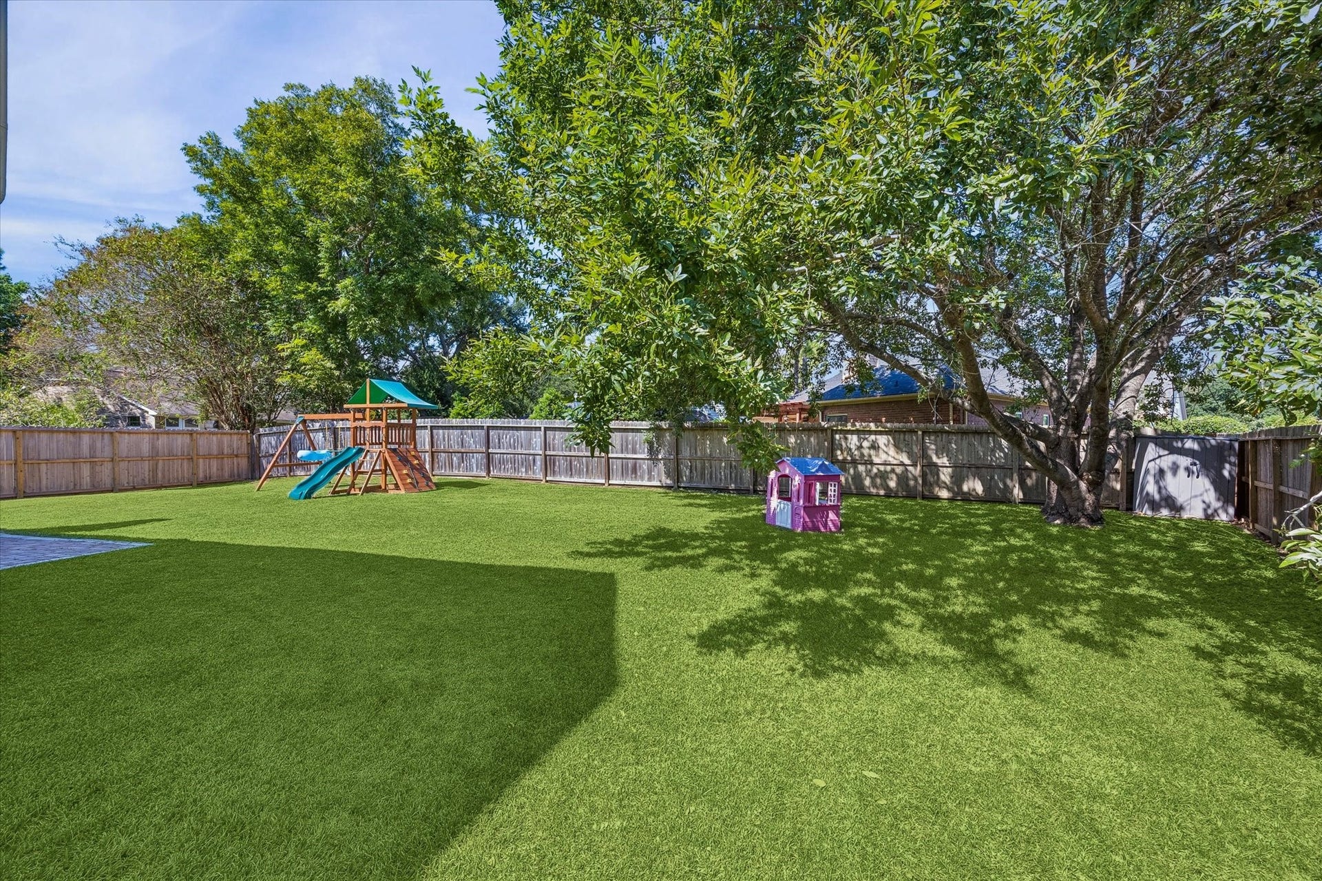 1043 Danforth Drive, Houston, TX 77062 Expansive backyard with lush greenery, complete with a playset and charming playhouse, perfect for family fun and outdoor activities.