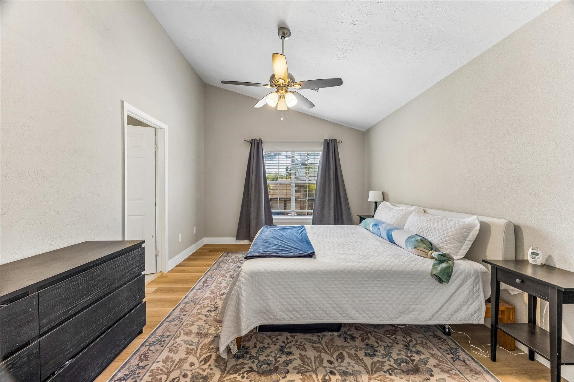 1043 Danforth Drive, Houston, TX 77062 Spacious Primary bedroom with vaulted ceilings, featuring a large window for natural light, neutral tones, and a ceiling fan for comfort.