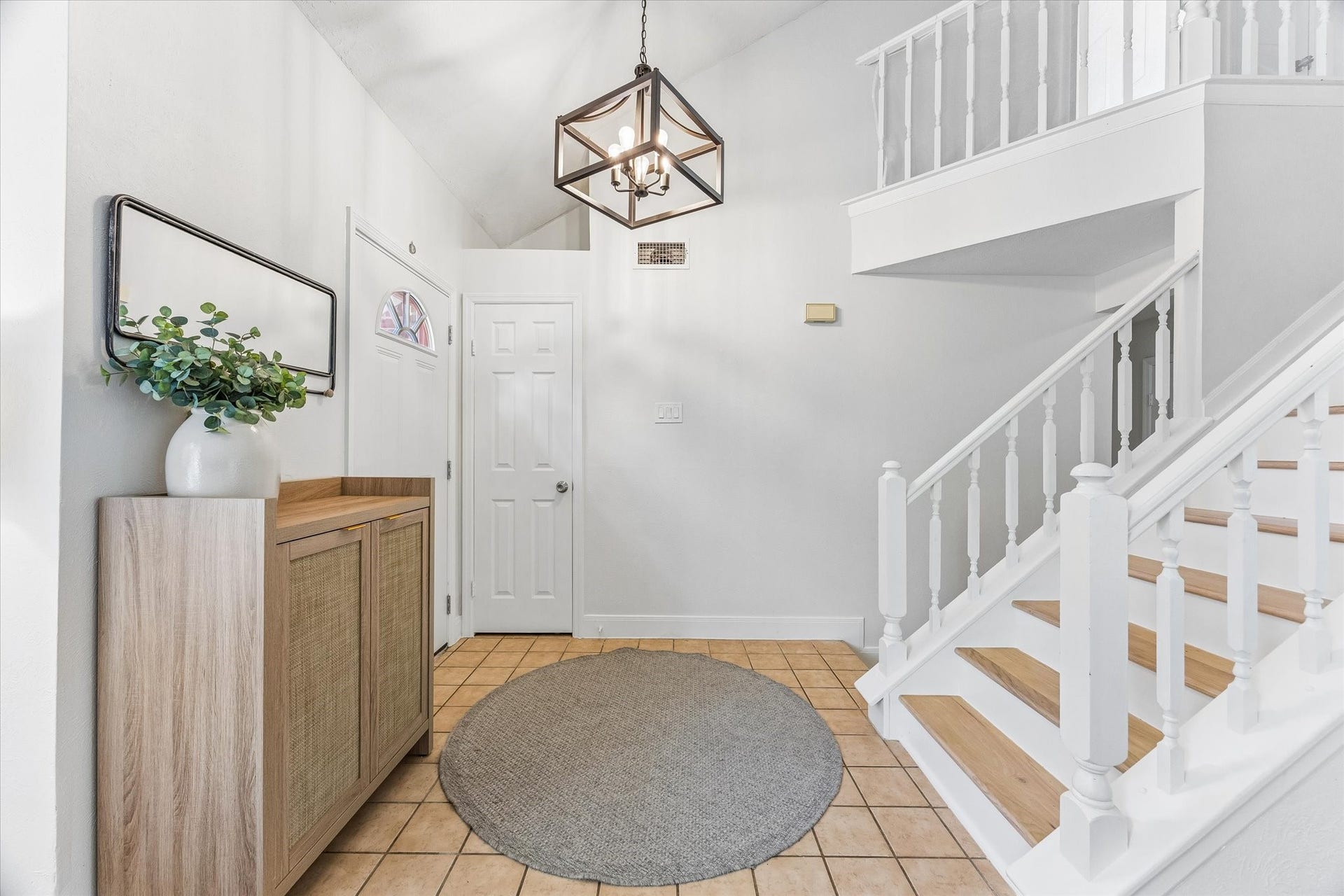 1043 Danforth Drive, Houston, TX 77062 Bright and welcoming entryway featuring a stylish light fixture, modern tile flooring, and a chic staircase with white railings.