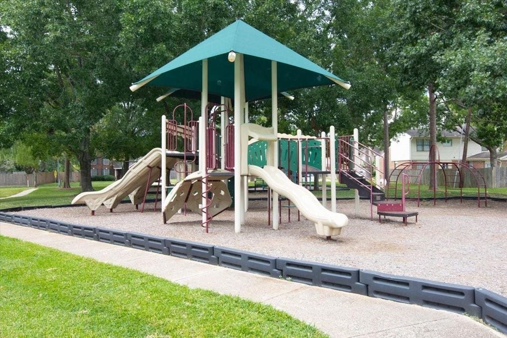 1043 Danforth Drive, Houston, TX 77062 Charming neighborhood playground featuring a modern play structure with slides, climbing areas, and shaded seating, surrounded by lush greenery.