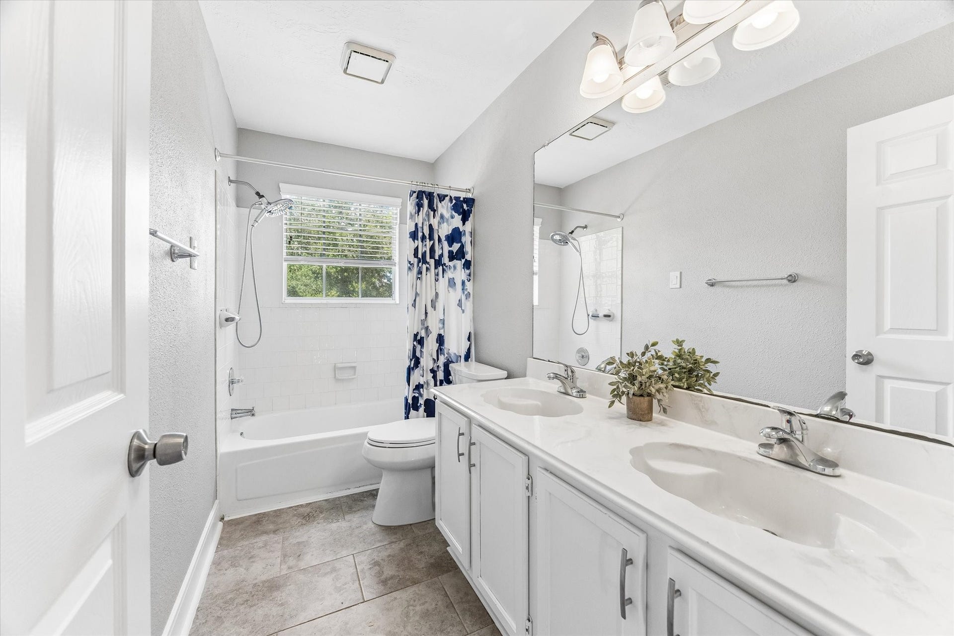 1043 Danforth Drive, Houston, TX 77062 Bright and inviting bathroom featuring a double vanity, modern fixtures, and a relaxing tub with a charming patterned shower curtain.
