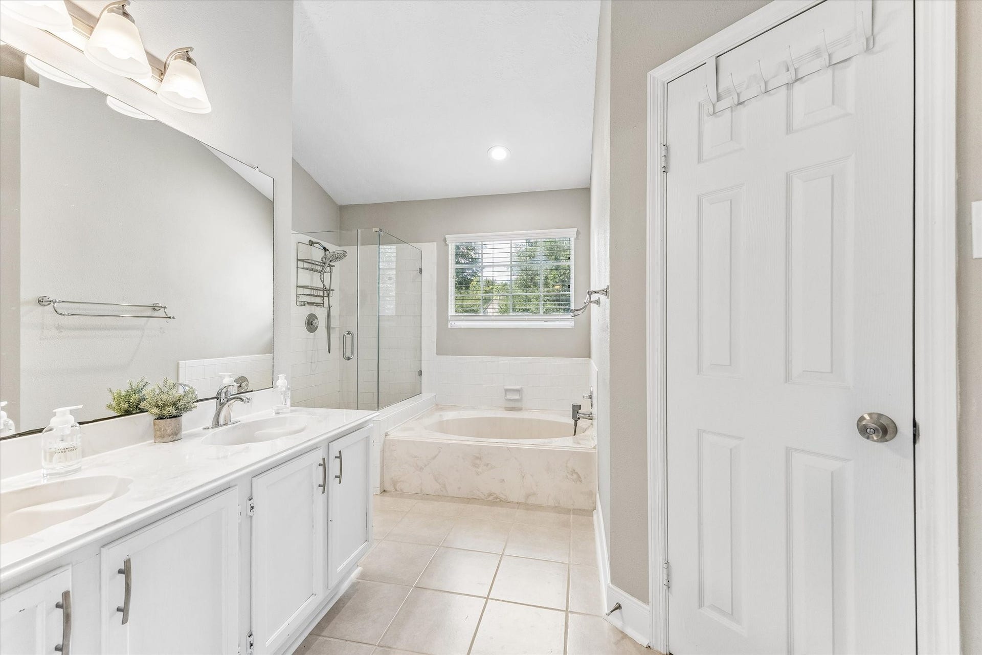 1043 Danforth Drive, Houston, TX 77062 Elegant bathroom featuring a spacious double vanity, a luxurious soaking tub, and a separate glass-enclosed shower, all illuminated by natural light through a large window.