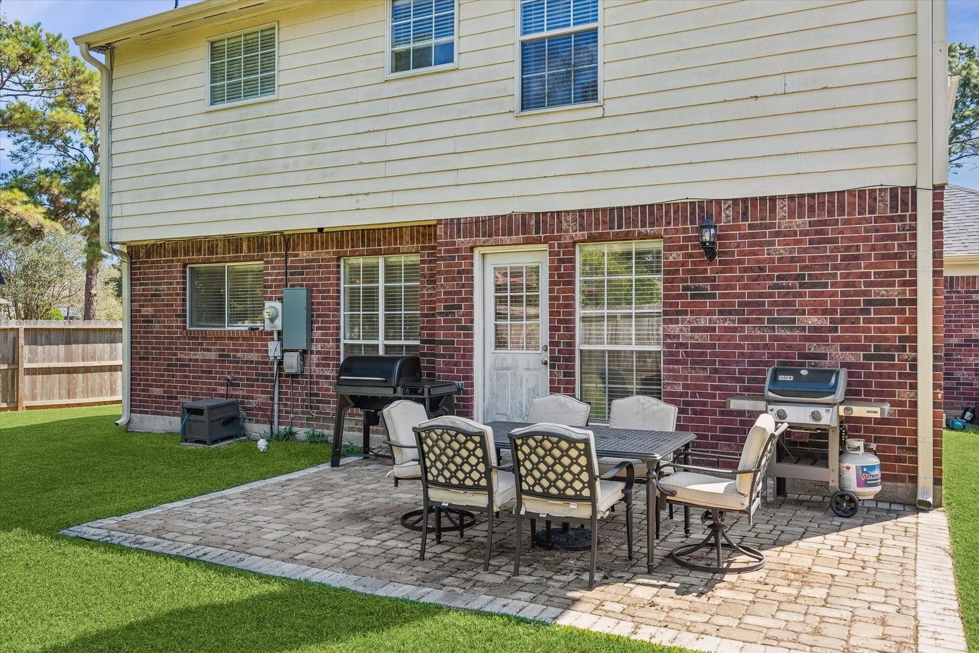 1043 Danforth Drive, Houston, TX 77062 Charming backyard patio with brick accents, featuring a spacious seating area perfect for outdoor dining and entertaining, complete with a grill and lush green lawn.