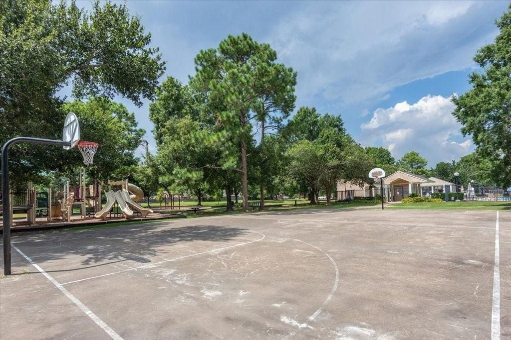 1043 Danforth Drive, Houston, TX 77062 Spacious outdoor recreation area featuring a basketball court, playground, and community center, surrounded by lush greenery.