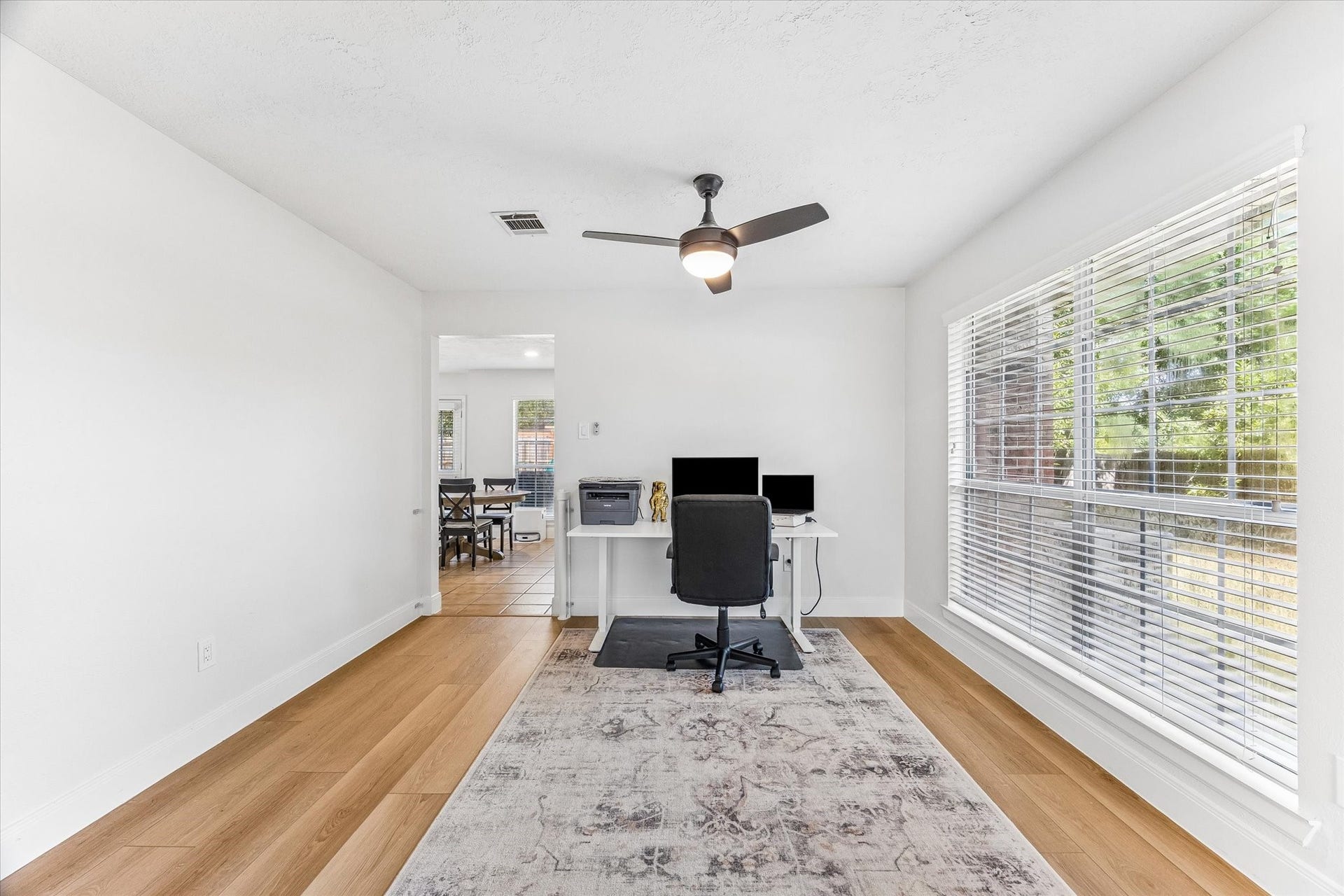 1043 Danforth Drive, Houston, TX 77062 Bright and inviting home office featuring large windows, sleek wood flooring, and a modern ceiling fan, providing a perfect workspace.