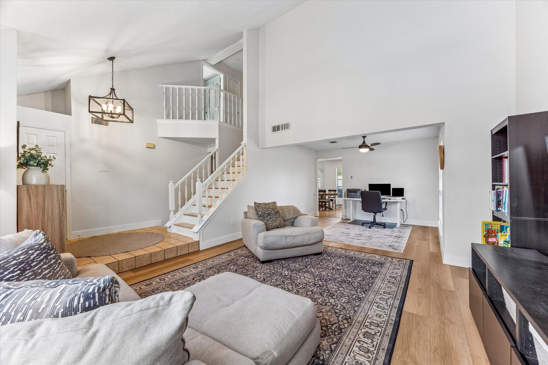 1043 Danforth Drive, Houston, TX 77062 Spacious living area with high ceilings and natural light, featuring a cozy sitting space, elegant staircase, and a versatile home office nook.