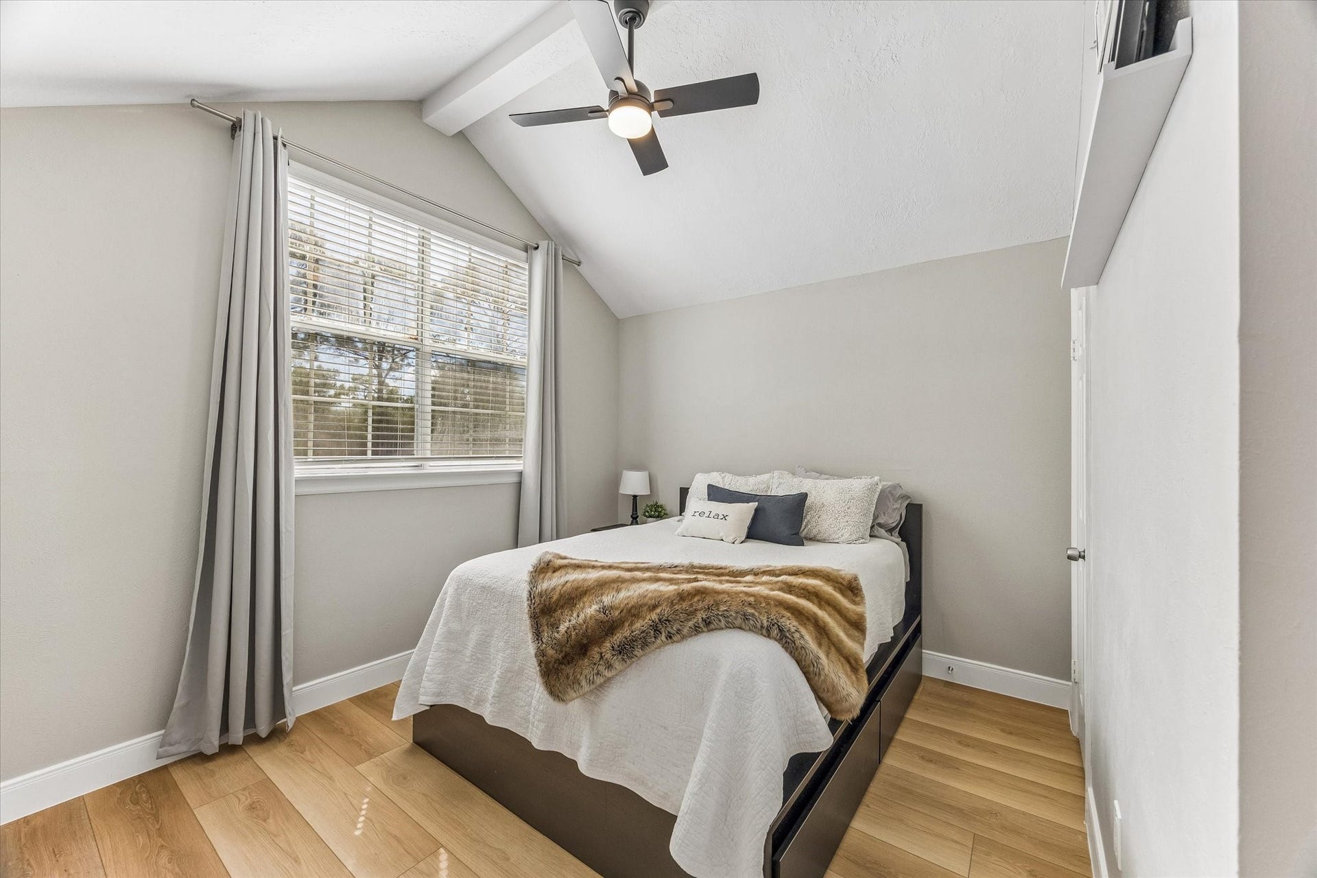 1043 Danforth Drive, Houston, TX 77062 Cozy bedroom with vaulted ceiling, featuring a large window for natural light, modern ceiling fan, and warm hardwood flooring.