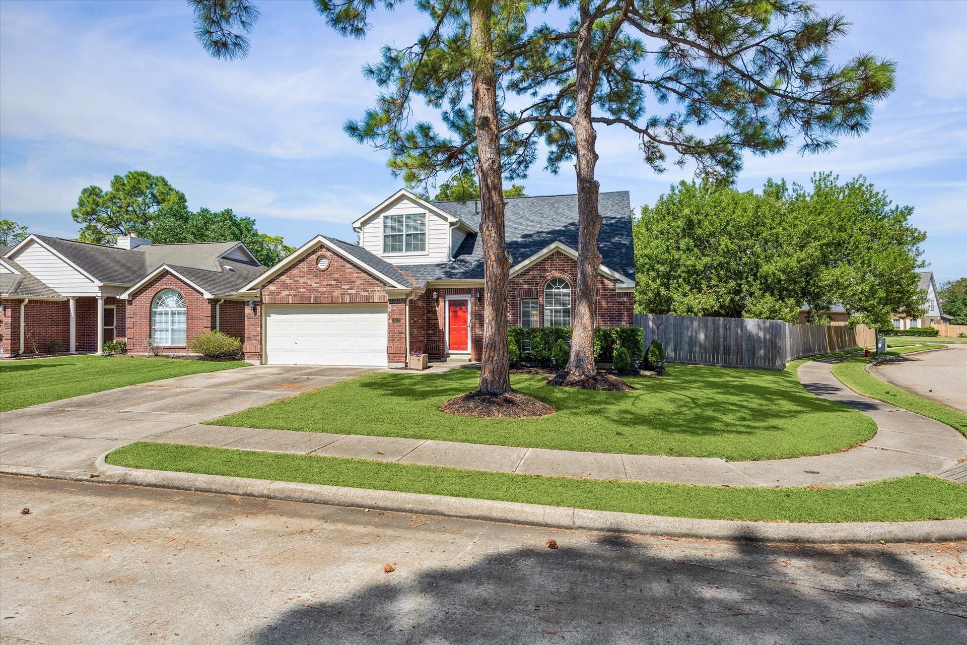 1043 Danforth Drive, Houston, TX 77062 Charming two-story brick home with a bright red door, nestled on a large corner lot with mature trees and well-maintained landscaping.