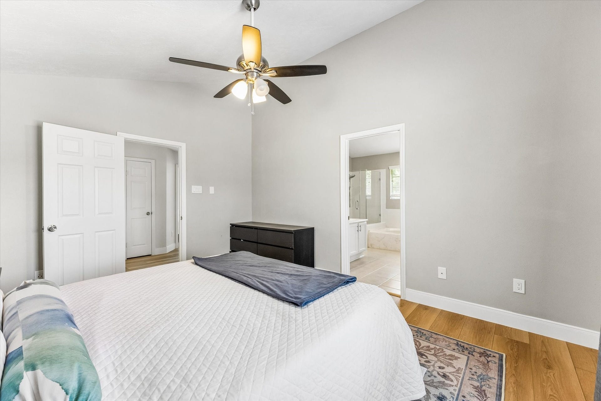 1043 Danforth Drive, Houston, TX 77062 Spacious bedroom with vaulted ceiling, modern ceiling fan, and en-suite bathroom access, featuring hardwood floors and neutral tones for a cozy retreat.
