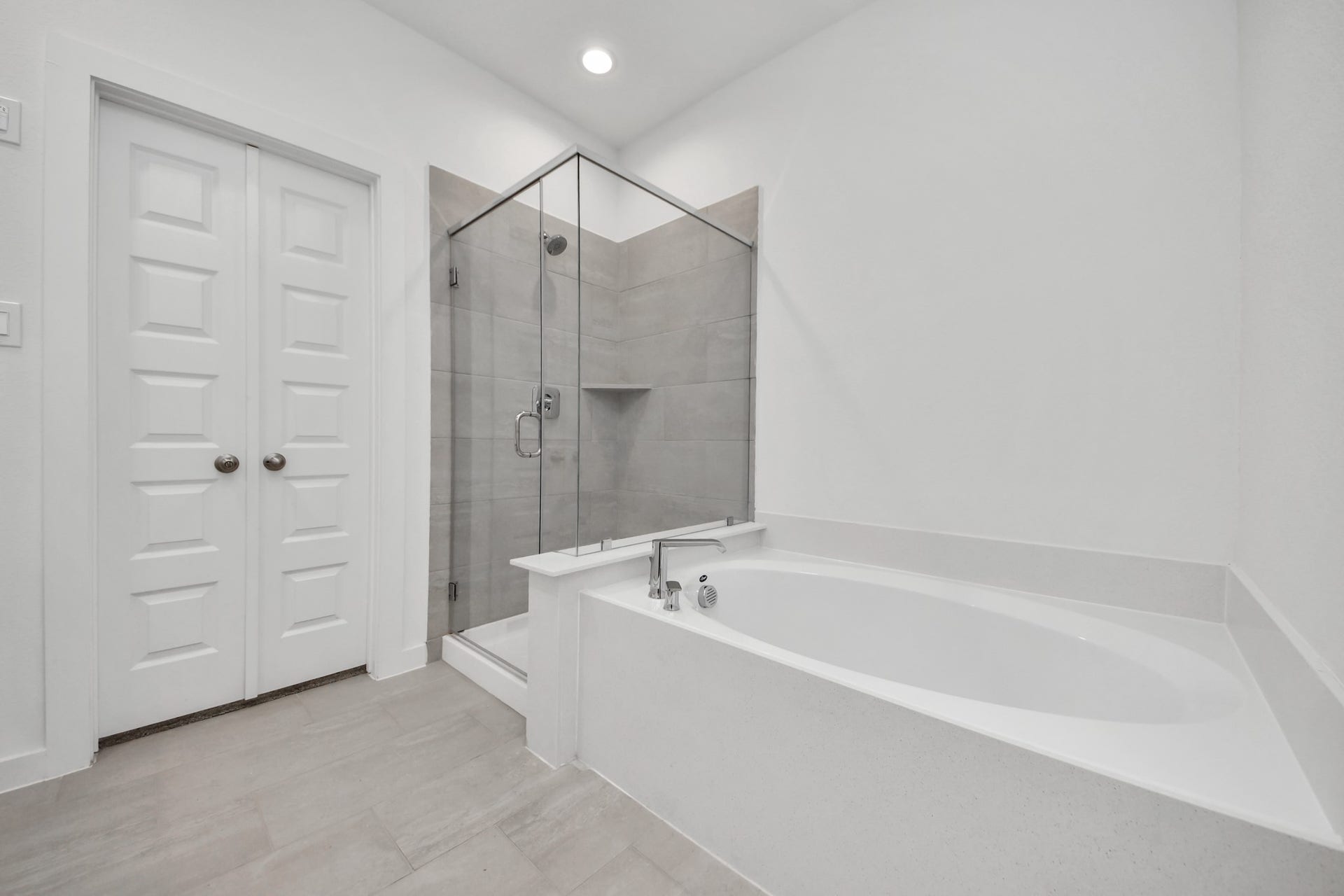 Indulge in a spa-like retreat within the confines of this primary bathroom. Delight in a spacious walk-in shower enveloped in stylish tile surround, unwind in a separate garden tub adorned with custom detailing. Sample photo of completed home with similar floor plan. Actual colors and selections may vary.