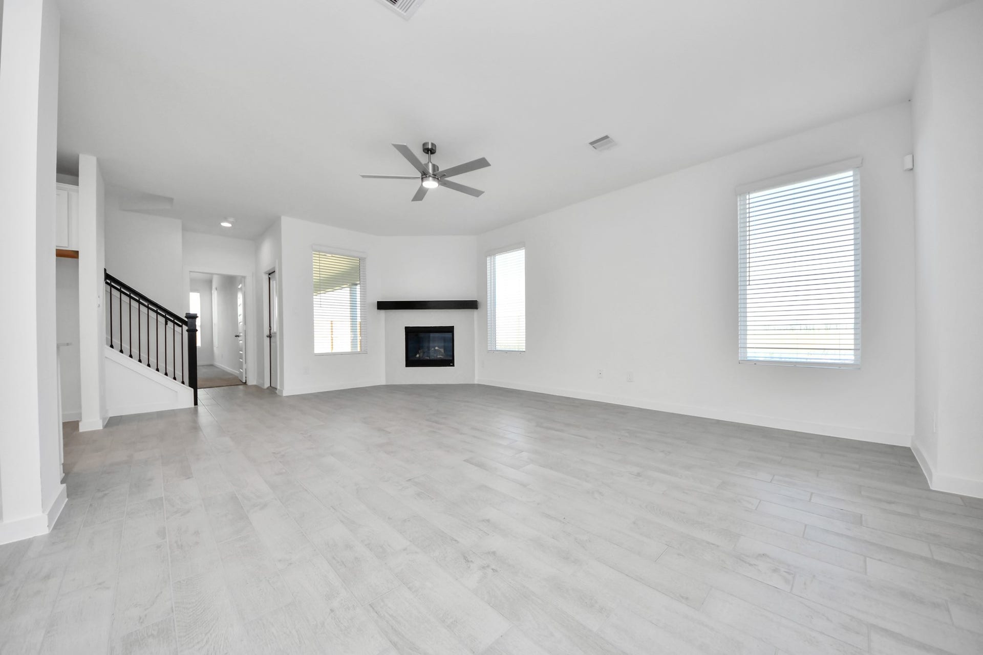 Relax and unwind in this inviting family room, illuminated by abundant natural light streaming in through tall windows, complemented by high ceilings and stunning flooring. Stay comfortable year-round with the gentle breeze from the ceiling fan, creating the perfect atmosphere for family gatherings.