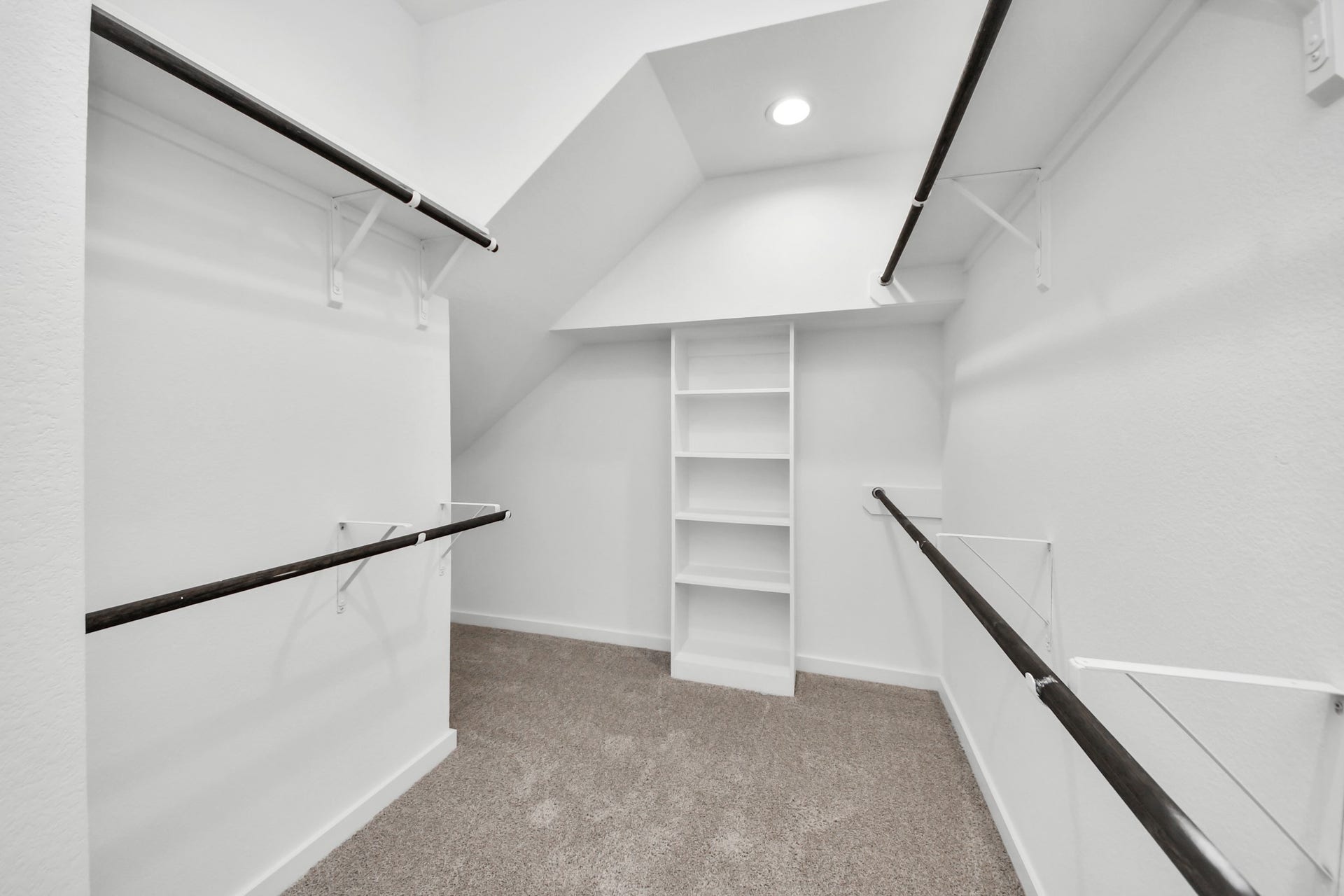 Walk-in closet that epitomizes luxury and practicality. This generously sized space features built-in shelving, offering abundant room for impeccable organization. High ceilings and recessed lighting create a bright and welcoming ambiance. Sample photo of completed home with similar floor plan. Actual colors and selections may vary.
