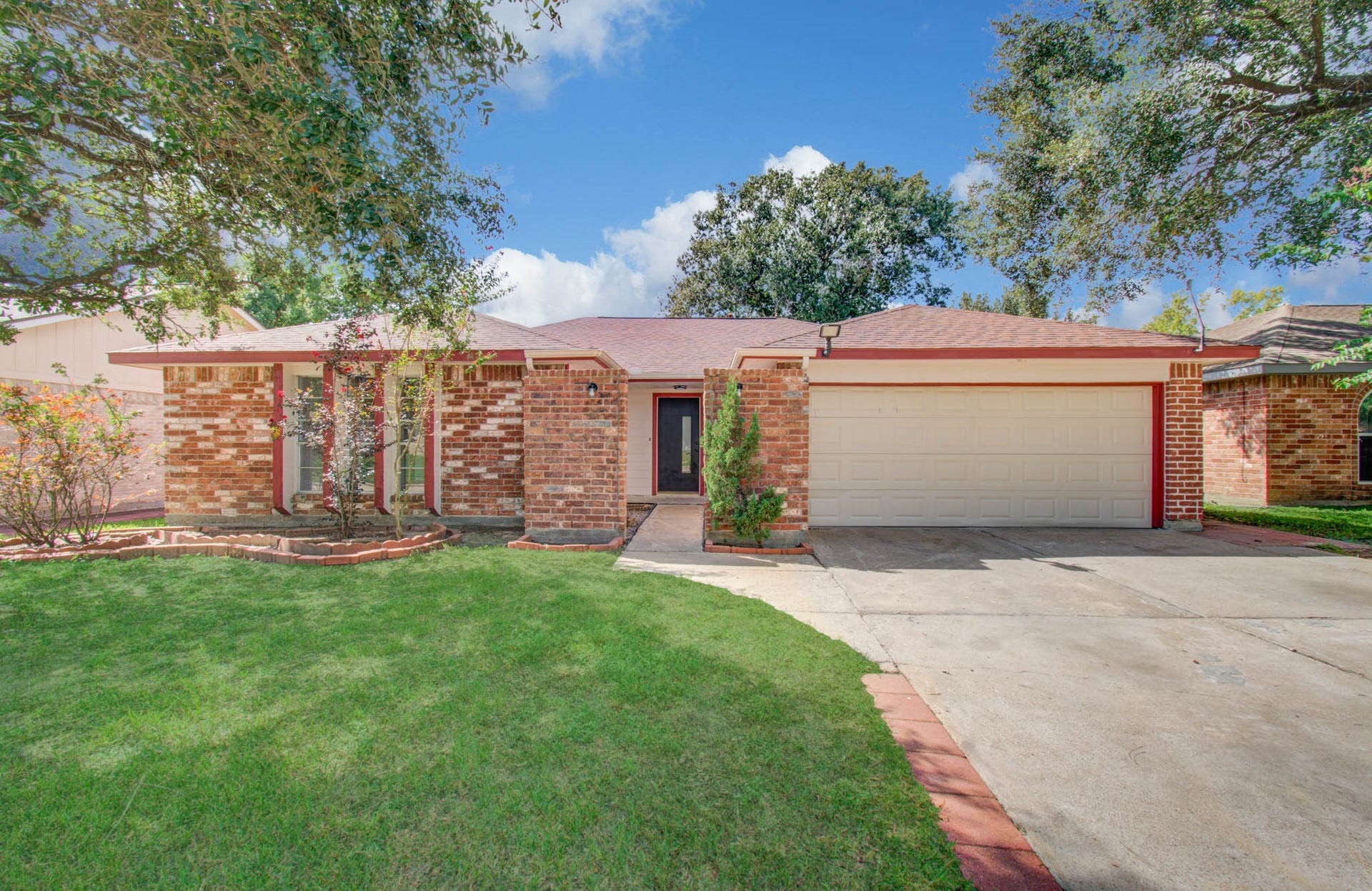 7319 Skybright Lane, Houston, TX 77095 Charming brick home with a spacious two-car garage, nestled on a well-maintained lawn with mature trees providing shade and curb appeal.