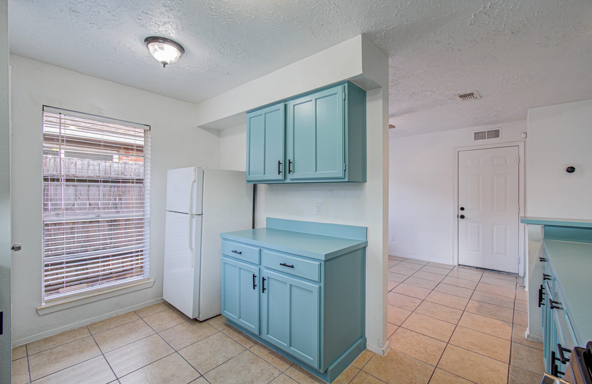 7319 Skybright Lane, Houston, TX 77095 Bright kitchen featuring charming blue cabinetry, a spacious layout, and ample natural light from a large window.