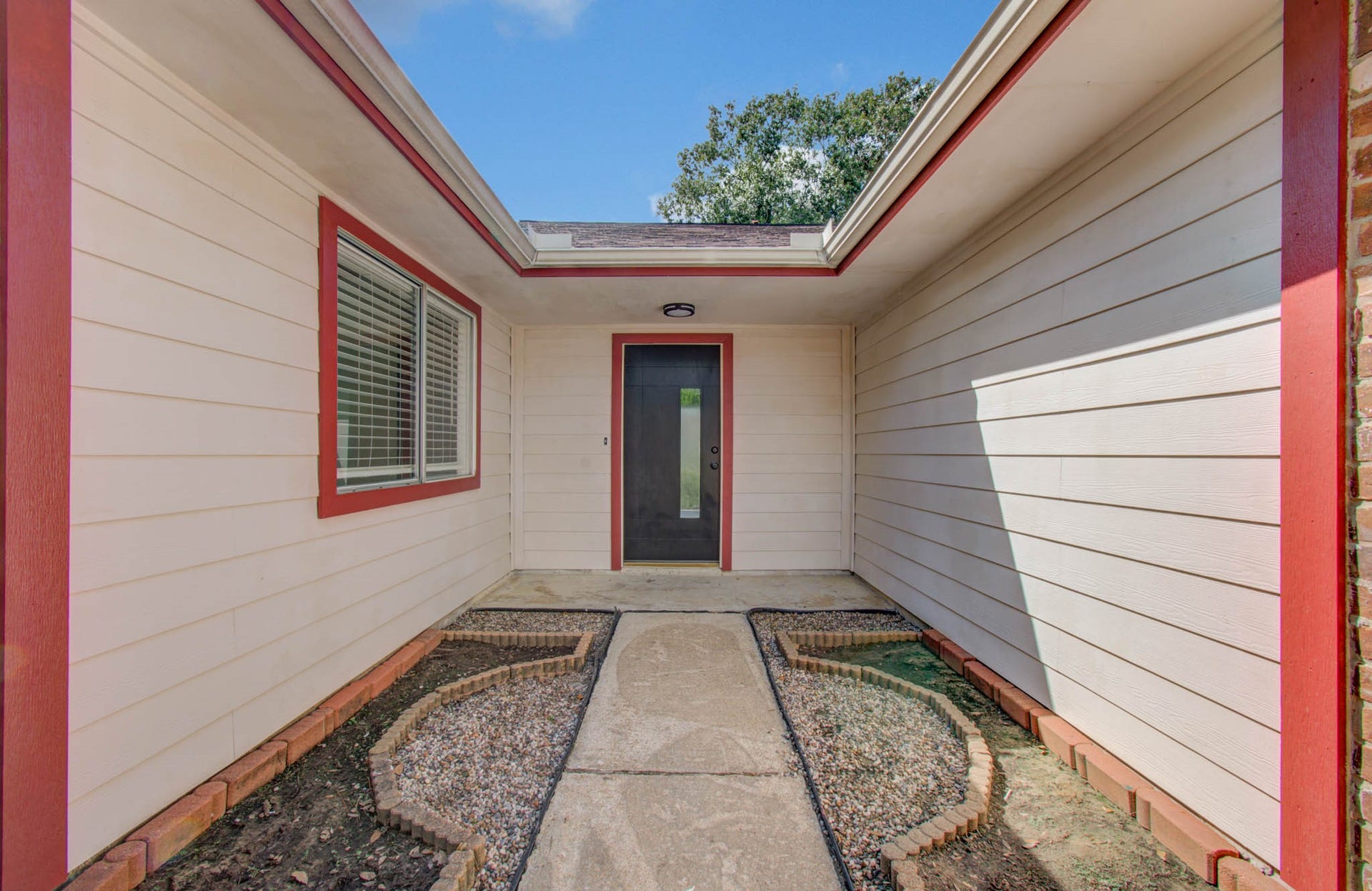 7319 Skybright Lane, Houston, TX 77095 Charming entrance with a welcoming pathway, framed by fresh landscaping and accented with bold red trim, leading to a modern glass door.