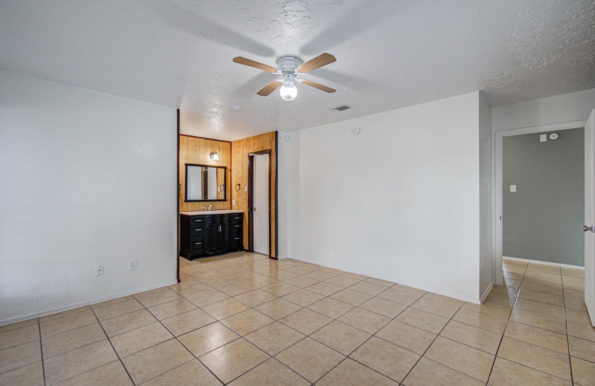 7319 Skybright Lane, Houston, TX 77095 Spacious room with tiled flooring, light neutral walls, and a ceiling fan, featuring a convenient vanity area with a sink and ample storage.