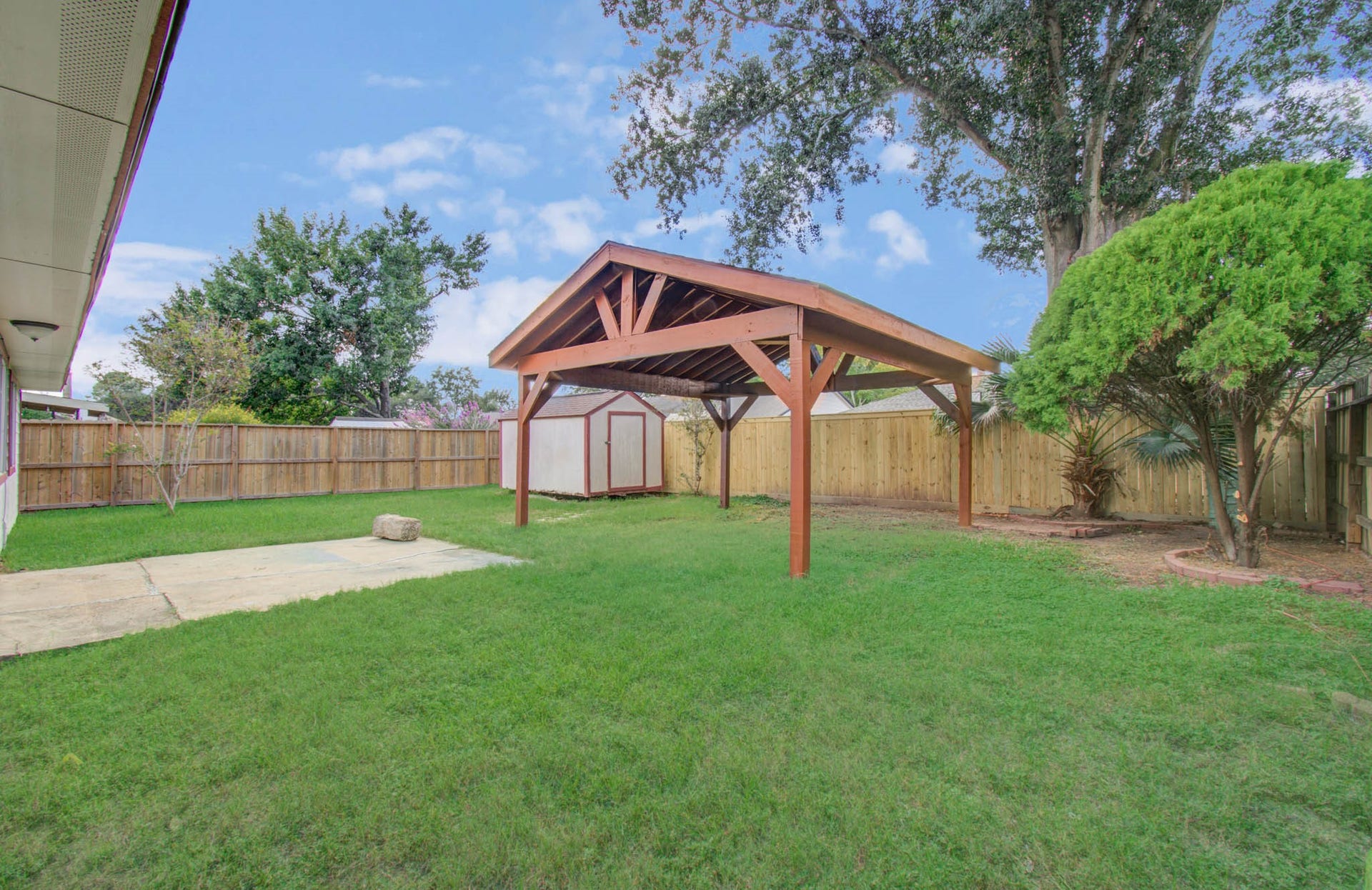 7319 Skybright Lane, Houston, TX 77095 Spacious backyard with a charming wooden pergola, lush green lawn, and privacy fence, perfect for outdoor gatherings.