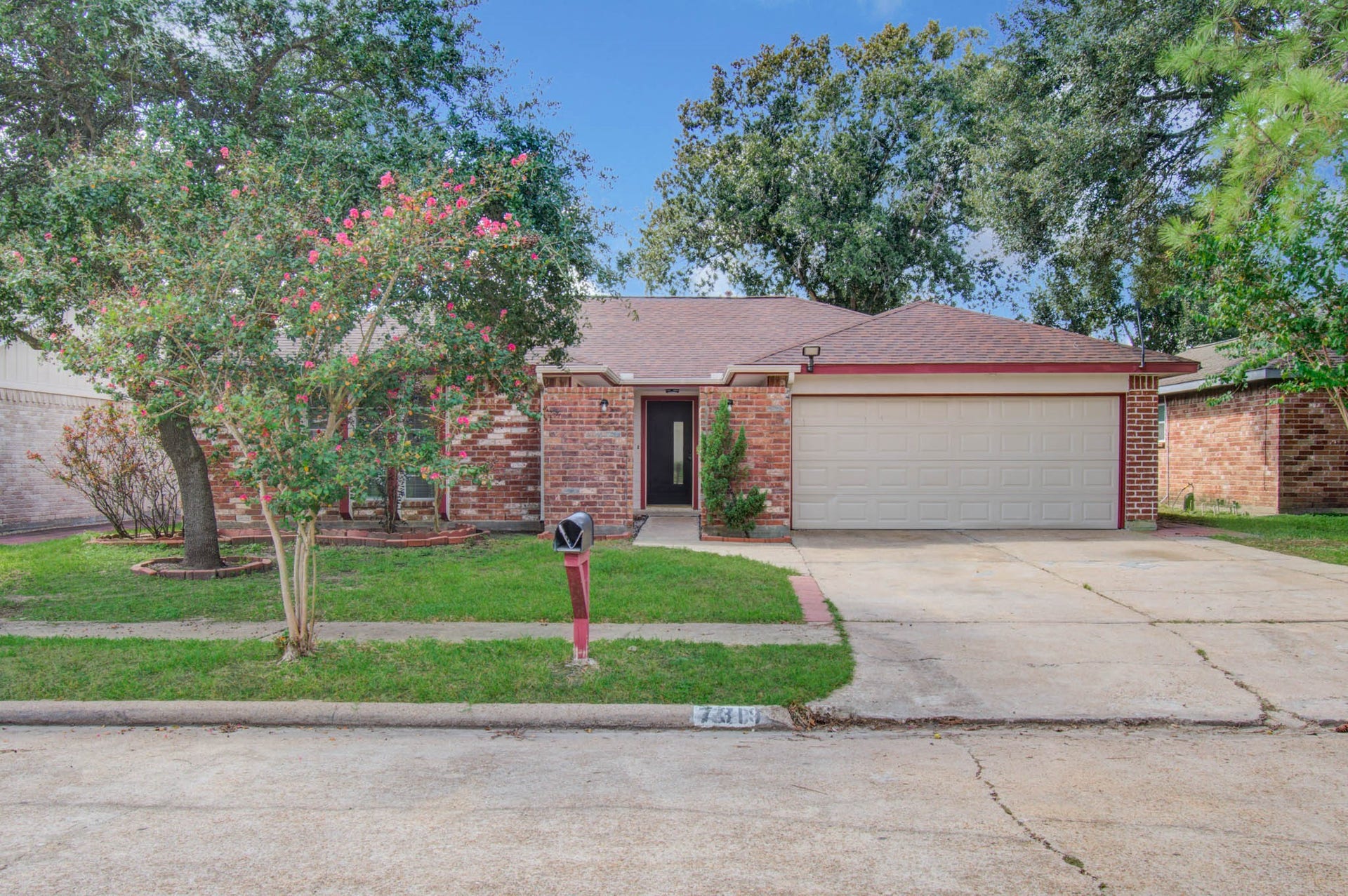 7319 Skybright Lane, Houston, TX 77095 Charming brick home with a spacious two-car garage, surrounded by lush greenery and mature trees, offering excellent curb appeal.