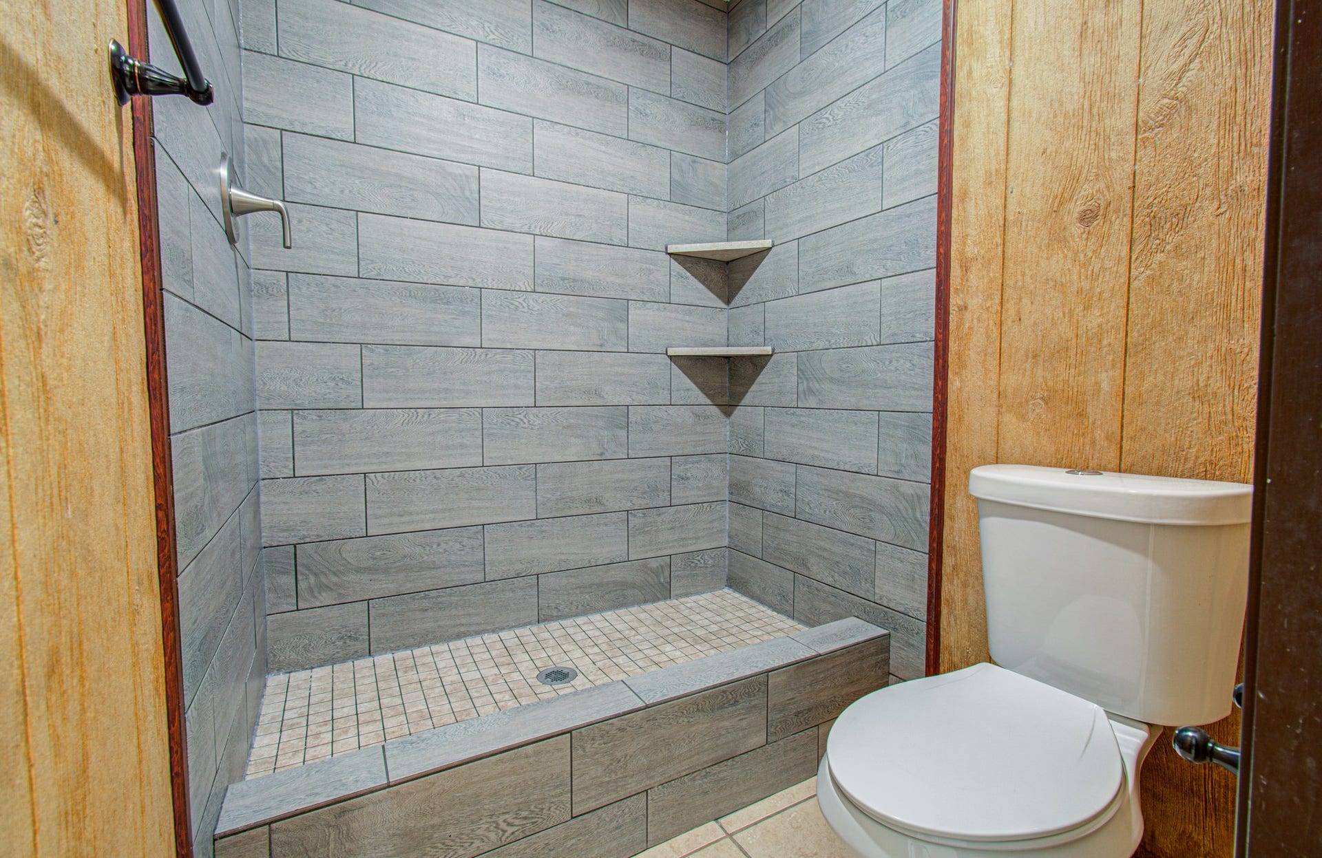 7319 Skybright Lane, Houston, TX 77095 Modern bathroom with a stylish, tiled walk-in shower and convenient built-in shelving, complemented by natural wood paneling.
