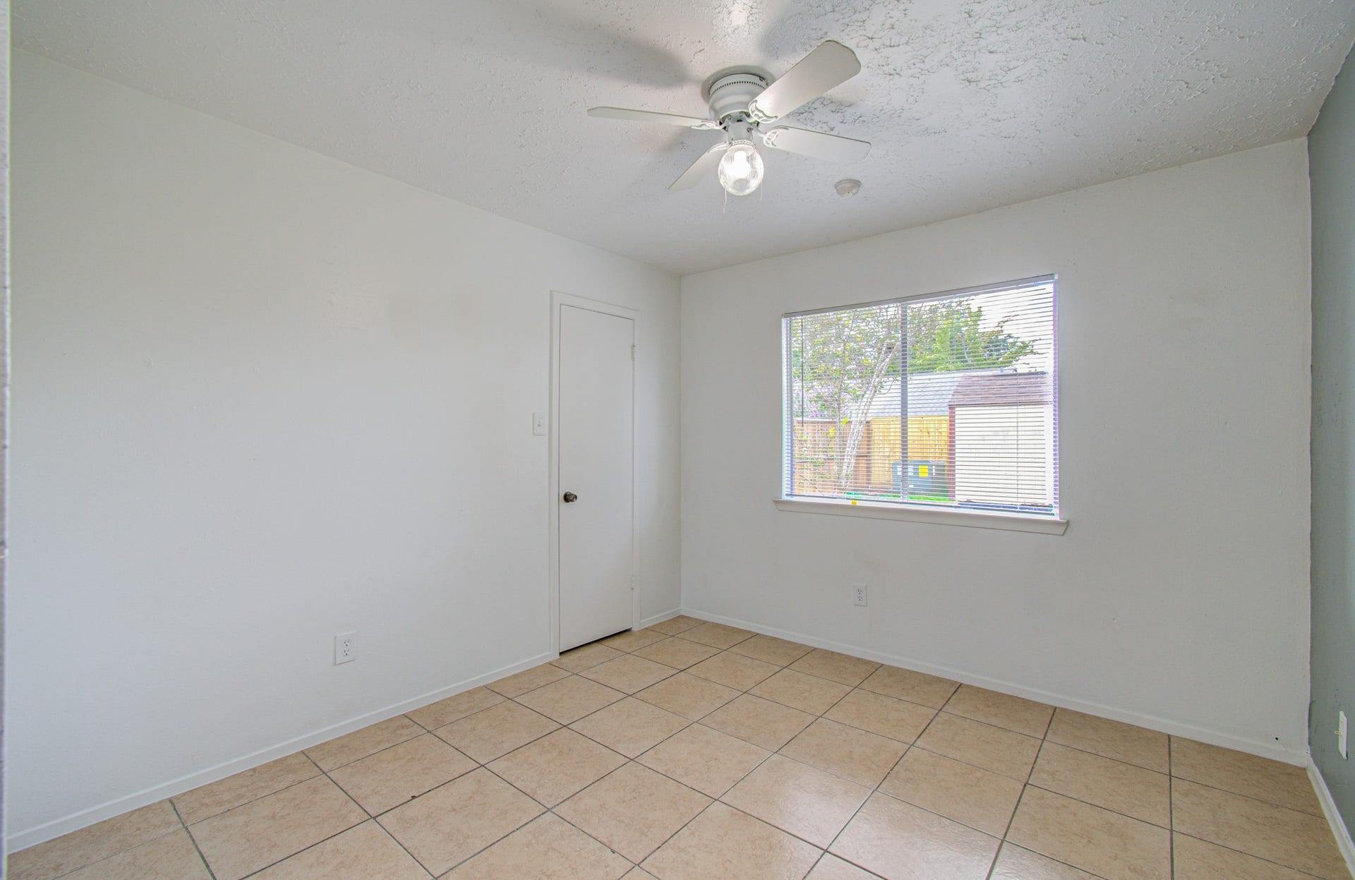 7319 Skybright Lane, Houston, TX 77095 Bright and airy room with neutral tile flooring, a large window for natural light, and a ceiling fan for comfort.