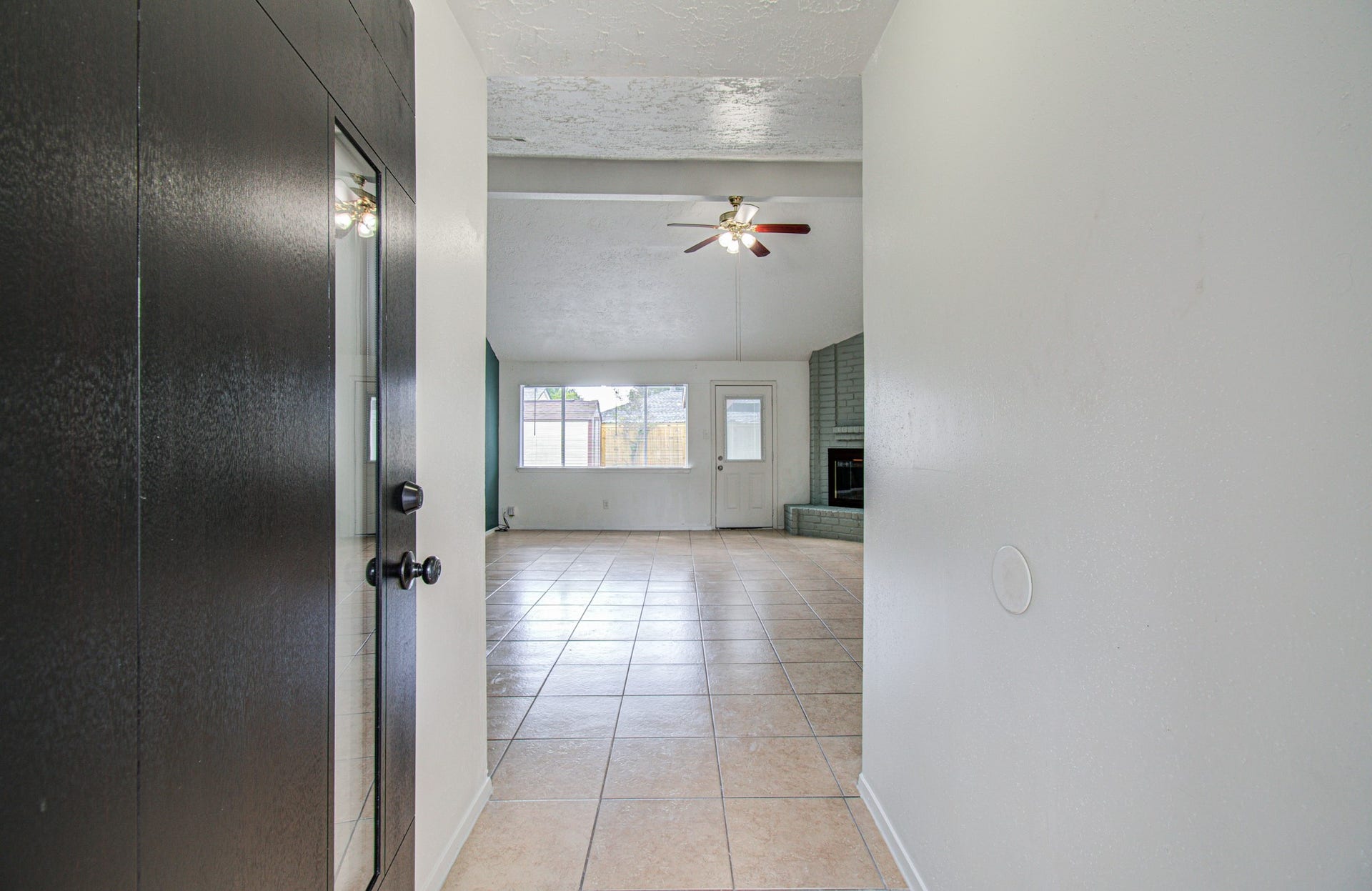 7319 Skybright Lane, Houston, TX 77095 Spacious entryway with elegant tile flooring leads to a bright living area featuring a cozy corner fireplace and ceiling fan, perfect for relaxing and entertaining.