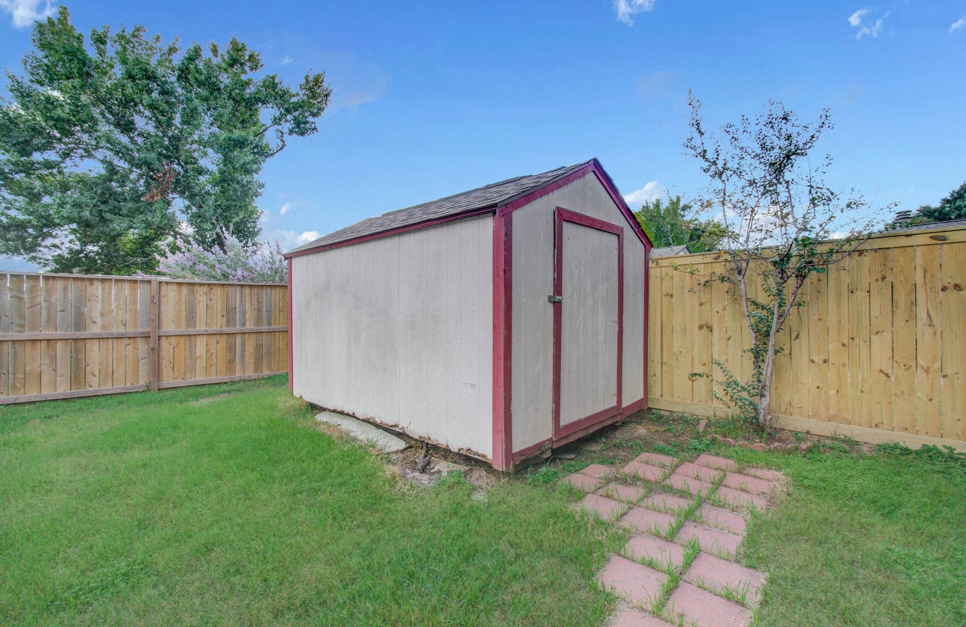 7319 Skybright Lane, Houston, TX 77095 Charming backyard shed with a rustic feel, surrounded by a well-maintained wooden fence and lush greenery, perfect for extra storage or a small workshop.