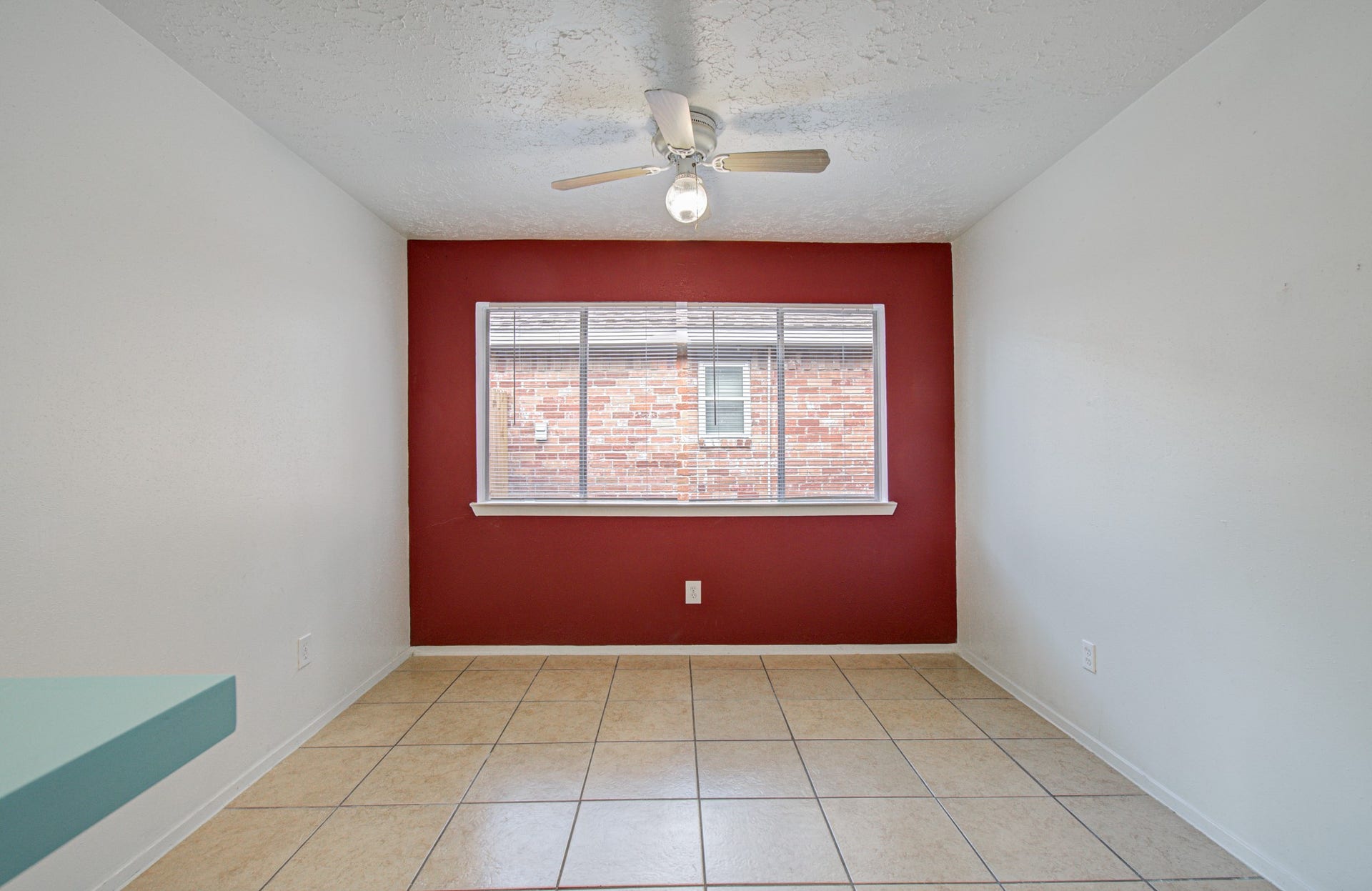 7319 Skybright Lane, Houston, TX 77095 Bright, cozy room featuring a bold red accent wall, large window, and ceiling fan, perfect for a dining area or office.