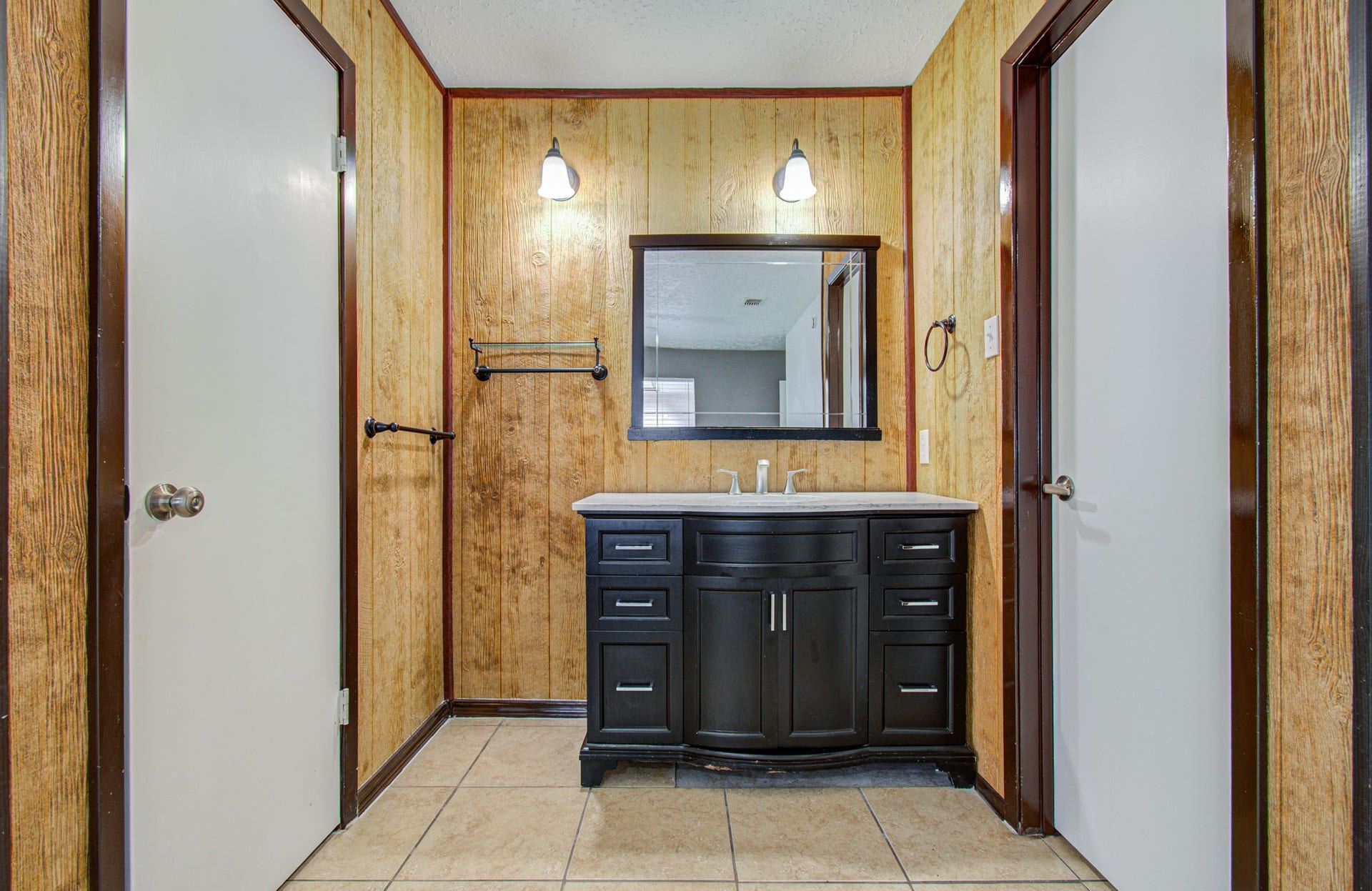 7319 Skybright Lane, Houston, TX 77095 Charming bathroom with rustic wood paneling features a sleek dark vanity, modern fixtures, and ample storage space.
