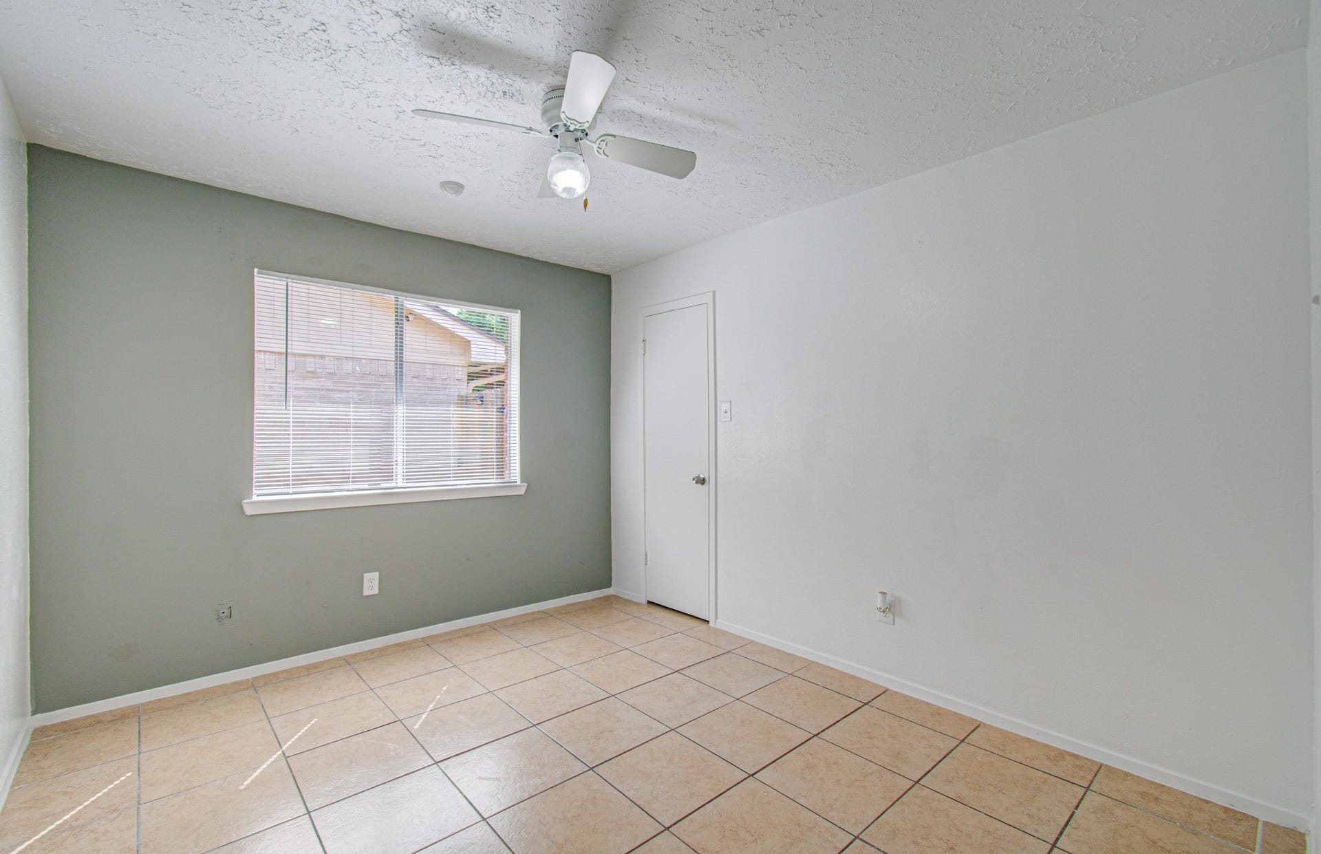 7319 Skybright Lane, Houston, TX 77095 Bright room with tile flooring, a ceiling fan, and a large window allowing natural light.