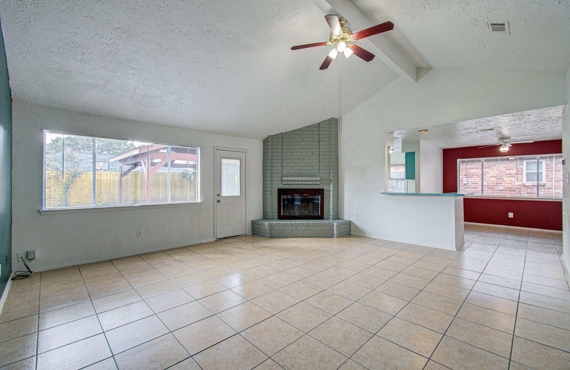 7319 Skybright Lane, Houston, TX 77095 Spacious living area featuring a vaulted ceiling with a ceiling fan, a cozy fireplace, and large windows for ample natural light, seamlessly connecting to an open dining space.