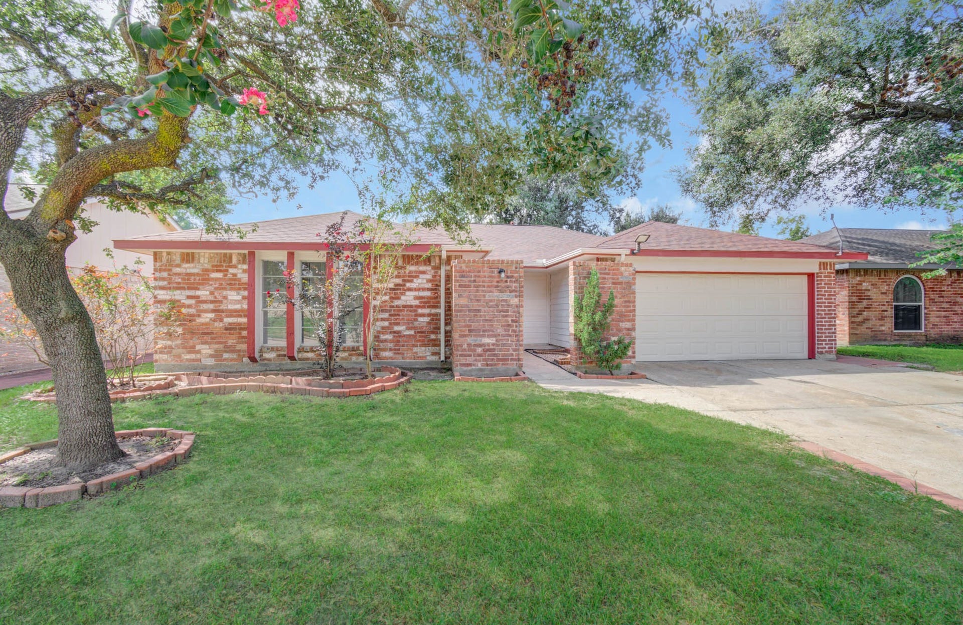 7319 Skybright Lane, Houston, TX 77095 Charming single-story brick home with a two-car garage, lush front yard, and mature trees providing shade and curb appeal.
