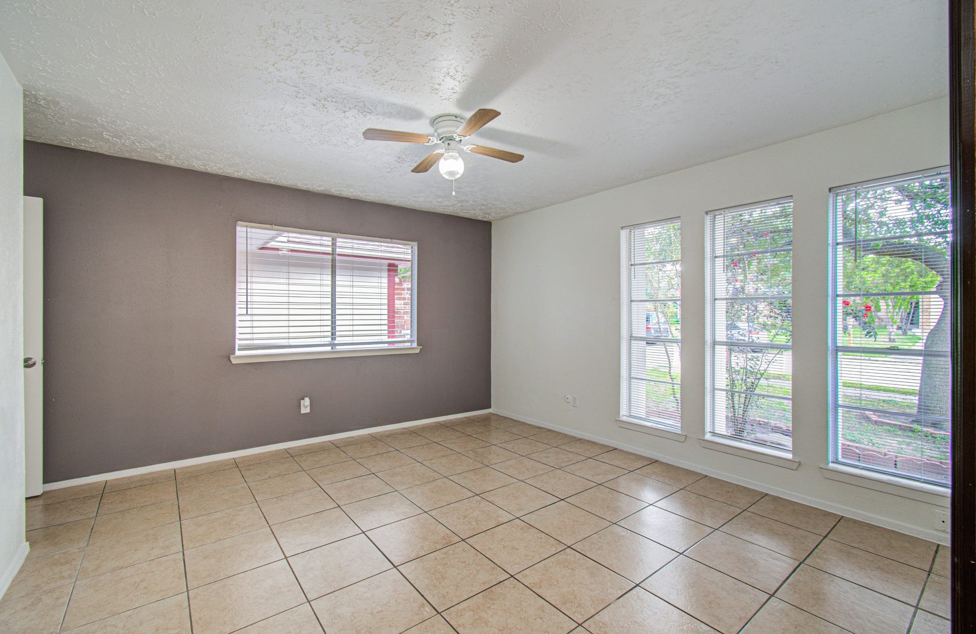 7319 Skybright Lane, Houston, TX 77095 Bright and airy room with large windows, neutral tile flooring, and a ceiling fan, perfect for a versatile living space.