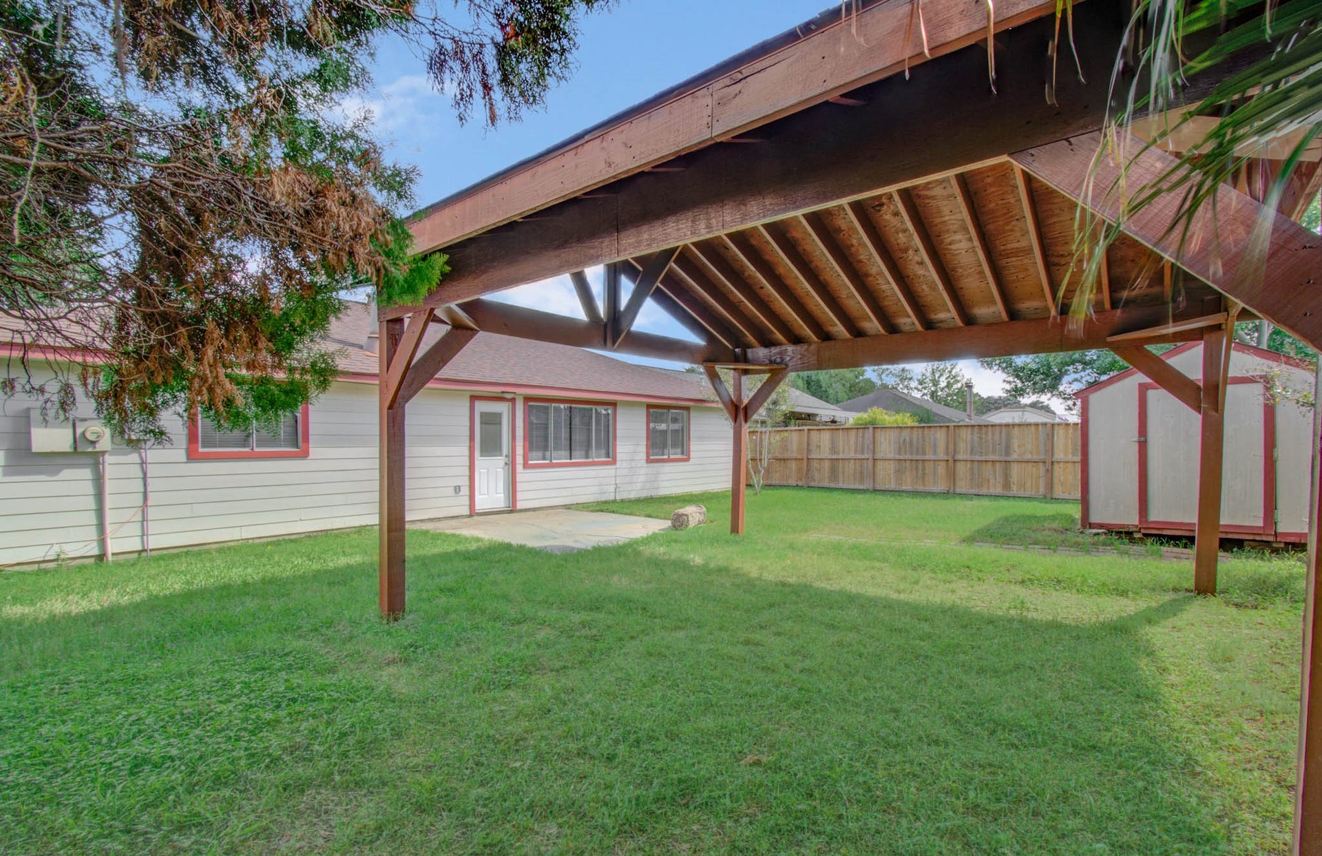 7319 Skybright Lane, Houston, TX 77095 Spacious backyard features a charming wooden pergola, perfect for outdoor gatherings, along with a storage shed and ample green space for relaxation or play.