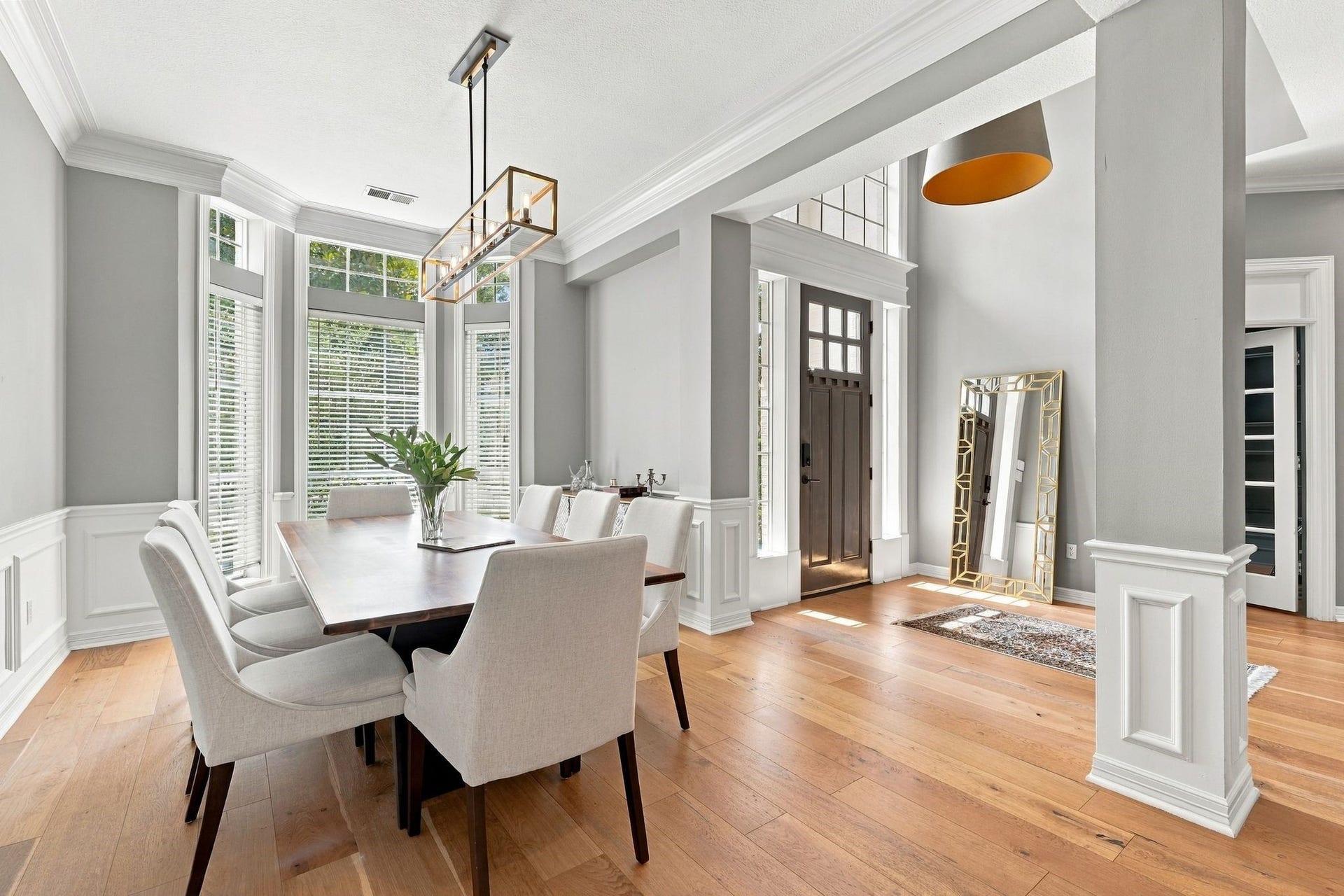 22 Hillside View Place, The Woodlands, TX 77381 The sophisticated formal dining room showcases extensive millwork, hardwood flooring, a contemporary light fixture, and bay windows bringing that bring in plenty of natural light.