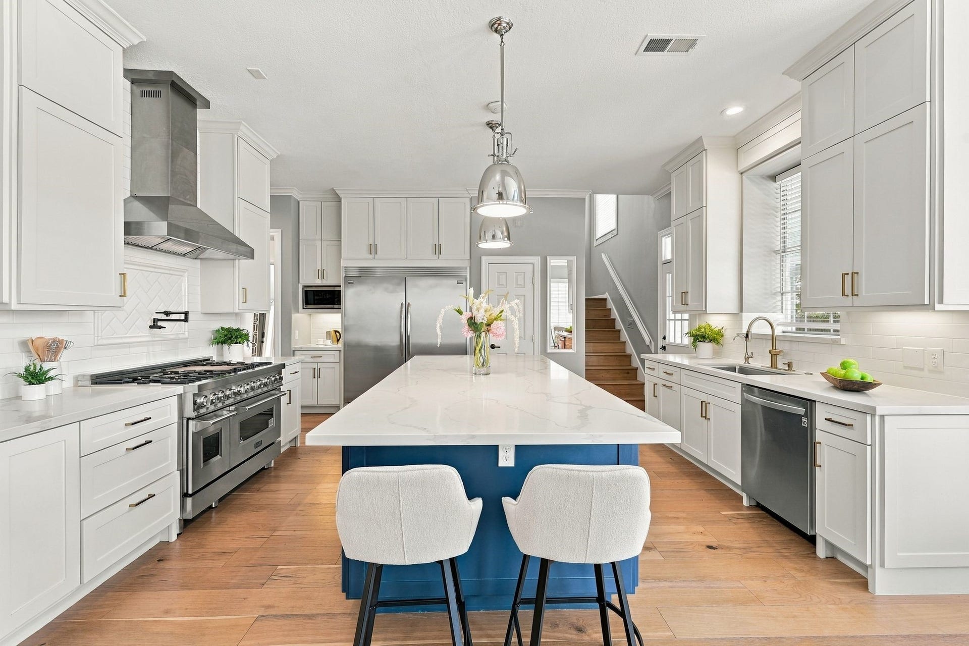 22 Hillside View Place, The Woodlands, TX 77381 The beautifully renovated chef's kitchen features an oversized statement island, quartz countertops, professional style appliances and abundant custom cabinetry.